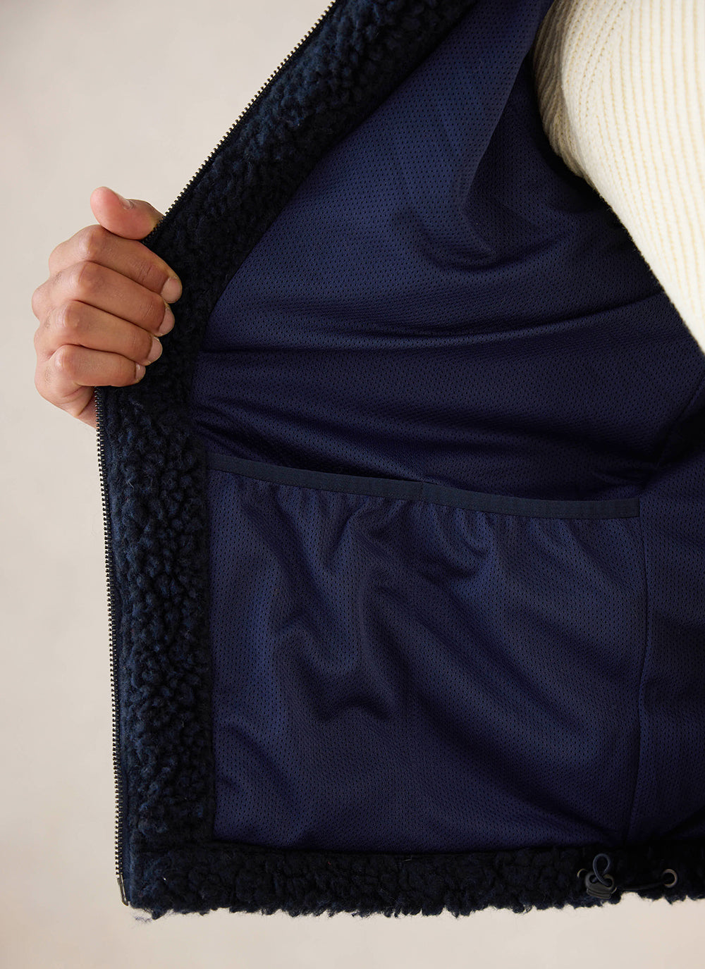 A close-up view showing the interior mesh lining and pocket of the navy wool fleece jacket by Percival.