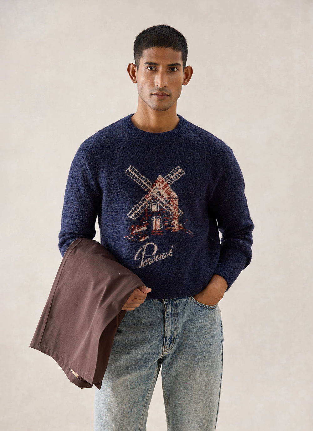 A model wears the navy Miller Boxy Jacquard Jumper from Percival featuring a windmill design, styled with blue jeans.