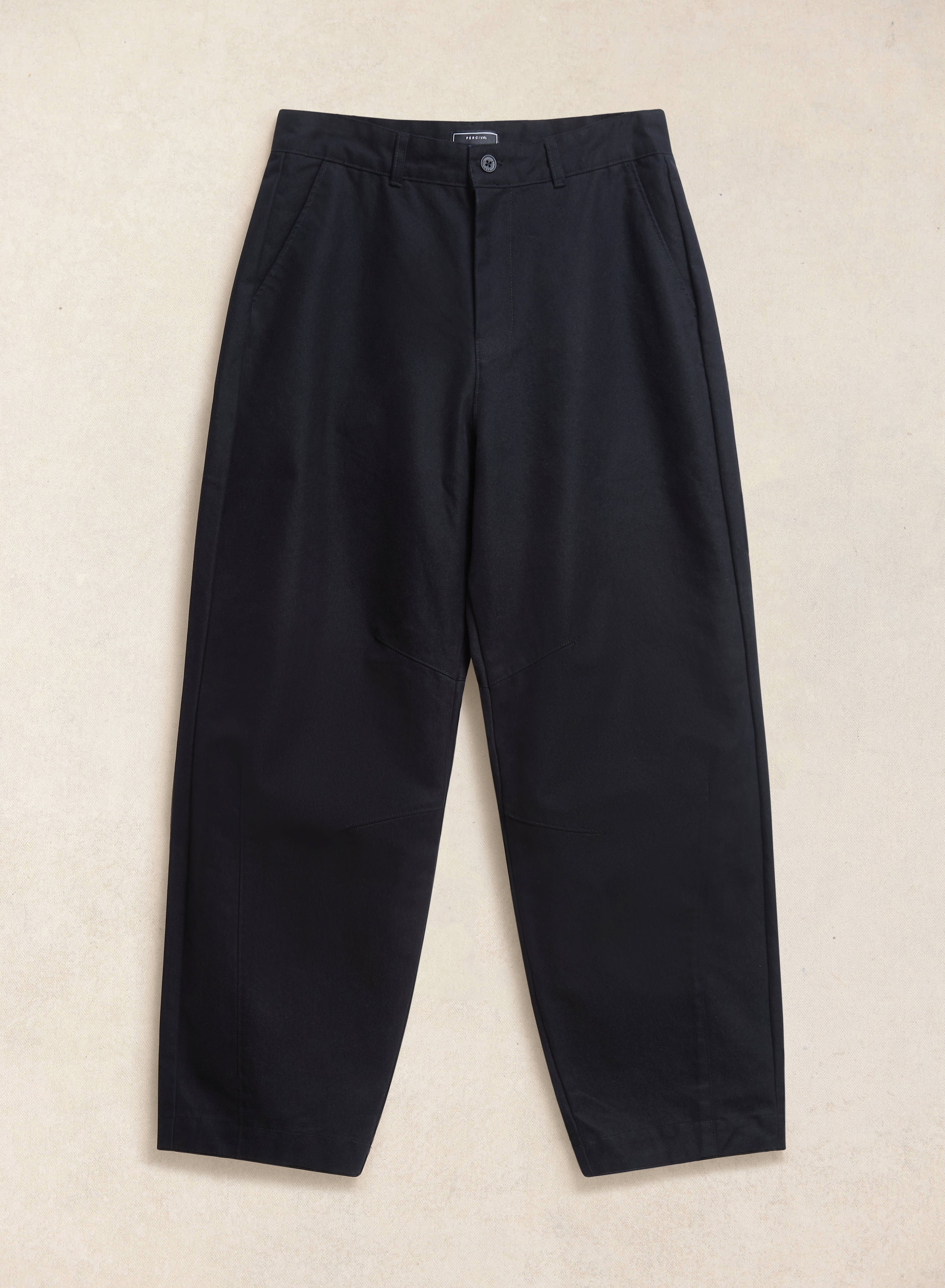 The black Percival Milo relaxed barrel leg trousers laid flat, showing the waistband, panel detailing, and side pockets.
