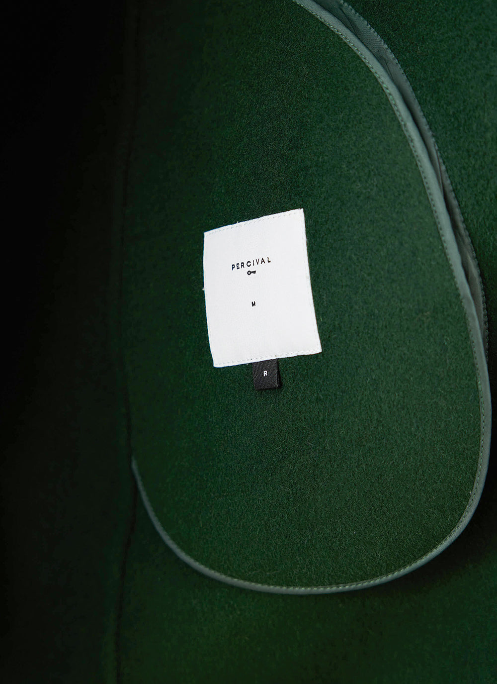 Close-up of the interior brand label inside the forest wool Minnesota Overcoat from Percival.