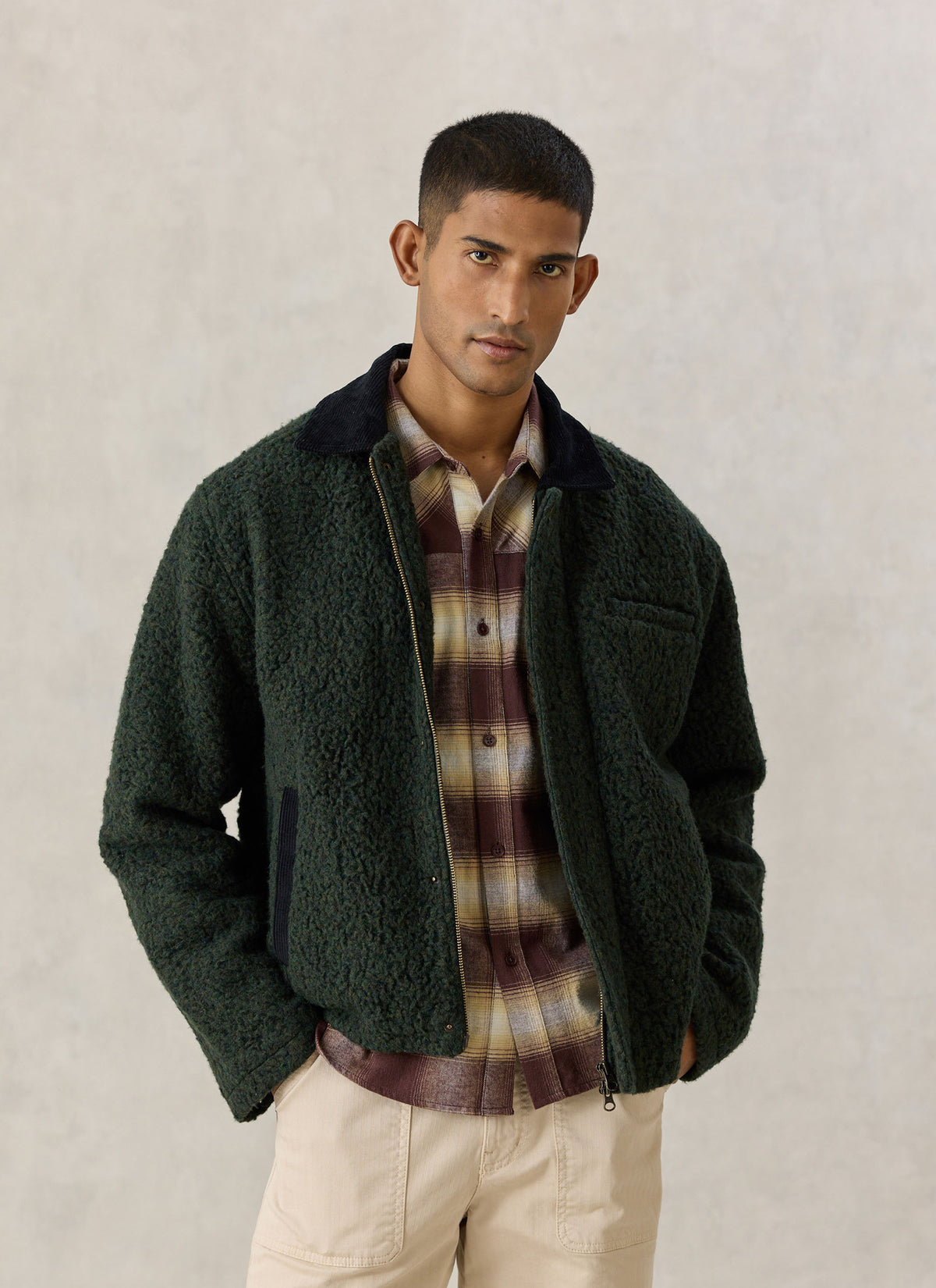 A model wearing the Percival forest green Murrey wool-blend fleece jacket with a contrasting cord collar and plaid shirt.