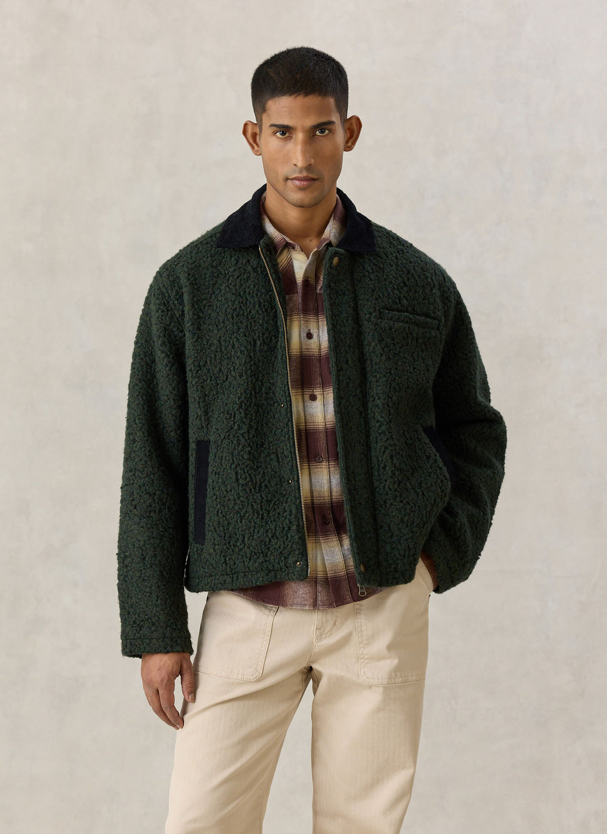 A model wearing the Percival forest green fleece jacket with a contrasting dark cord collar over a checked shirt.
