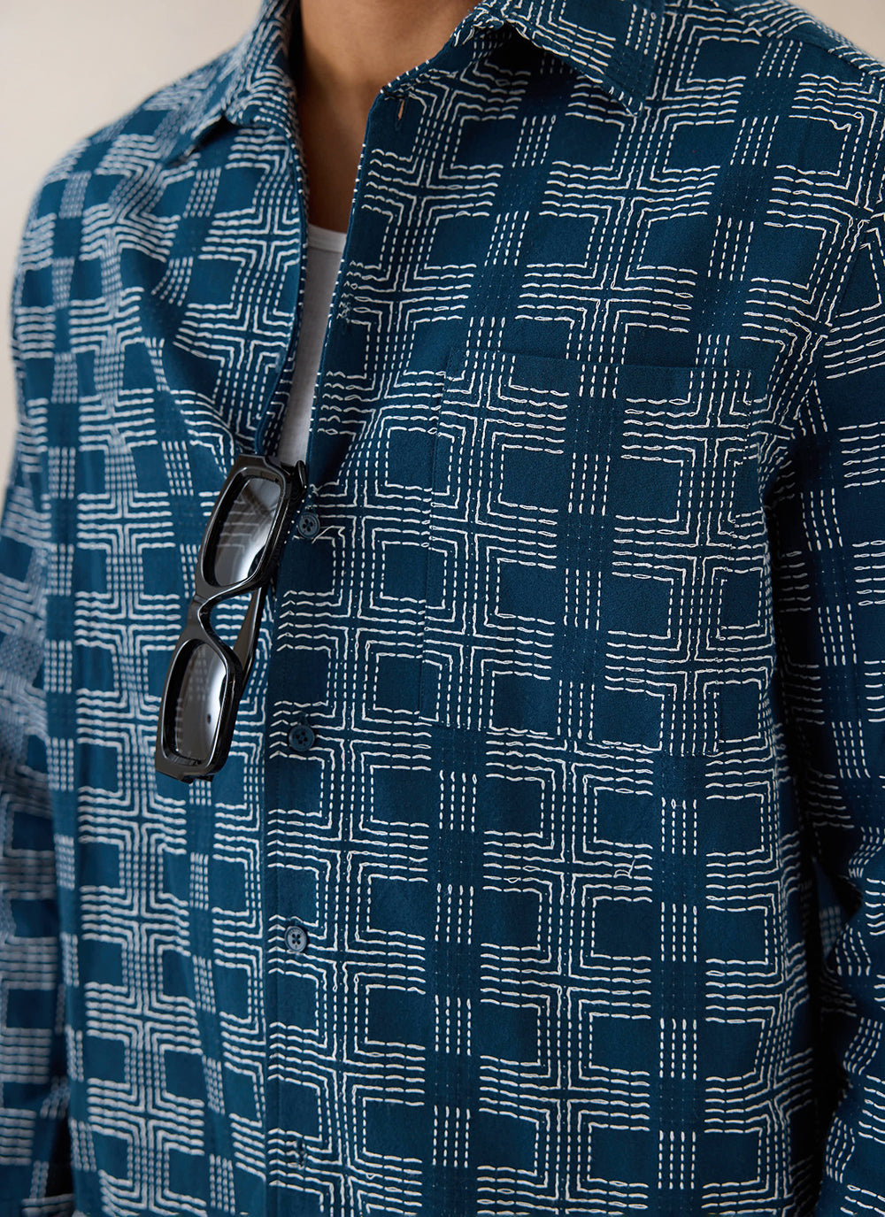 Close-up of a model wearing the navy Percival Nolan shirt, showing the patterned stitching and sunglasses on the placket.