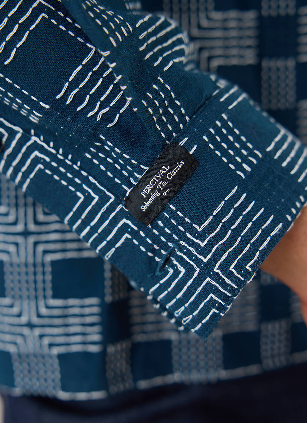 A close-up shot showing the navy jacquard cotton fabric and brand label of the Percival Nolan long sleeve shirt.