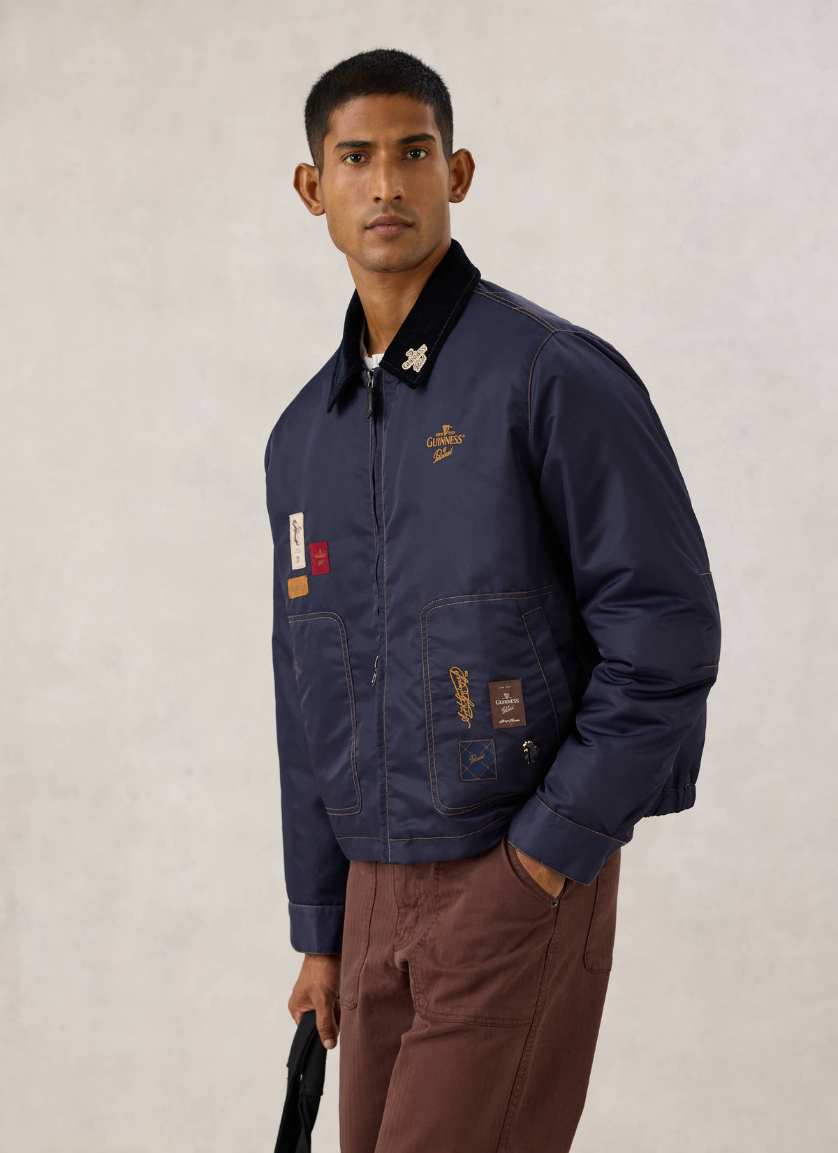 Model wearing the navy nylon Patchwork Embroidered Jacket from the Guinness x Percival collection.