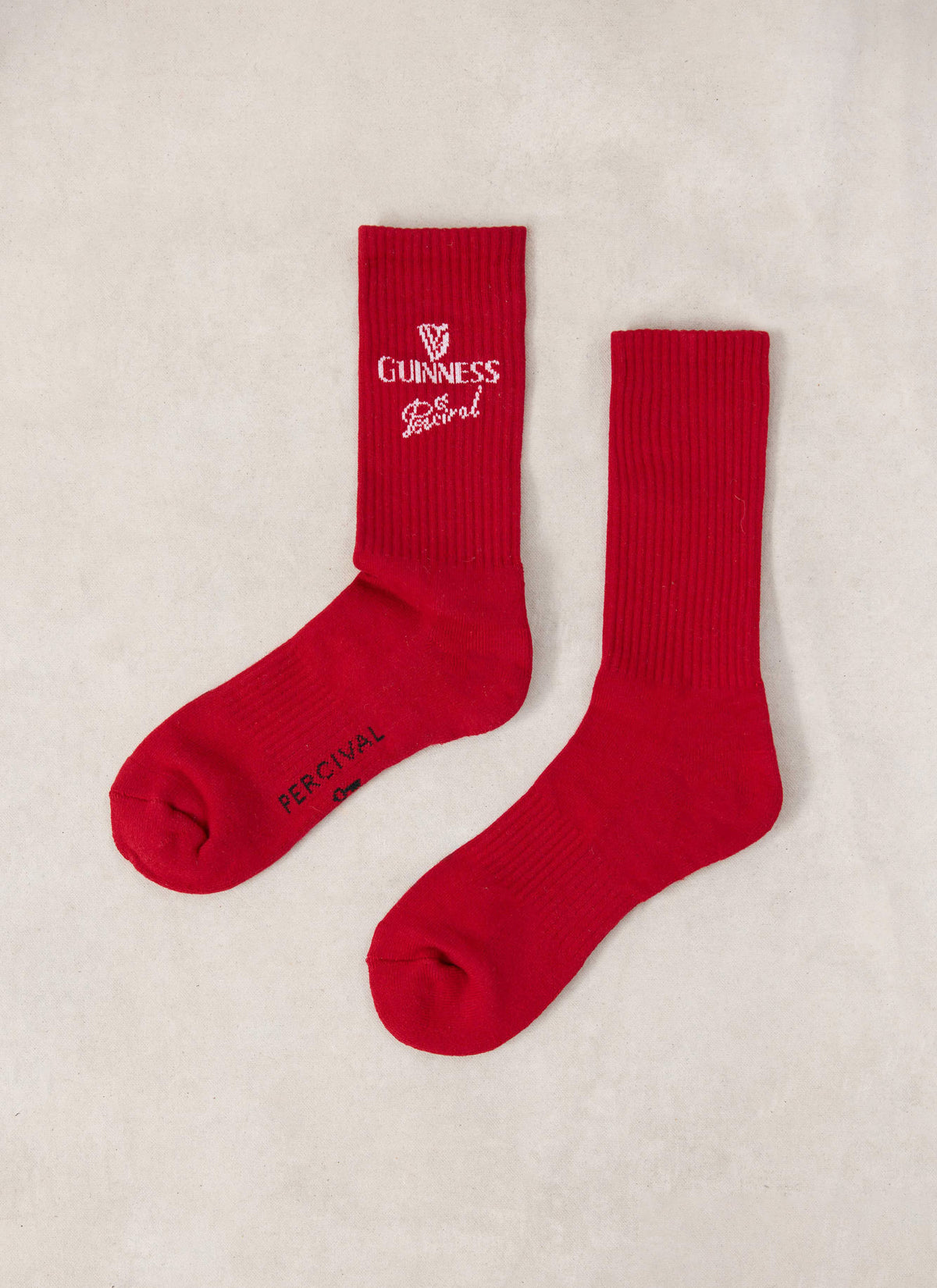 Flat lay of red Guinness x Percival ribbed crew socks featuring white logo detailing on a neutral background.