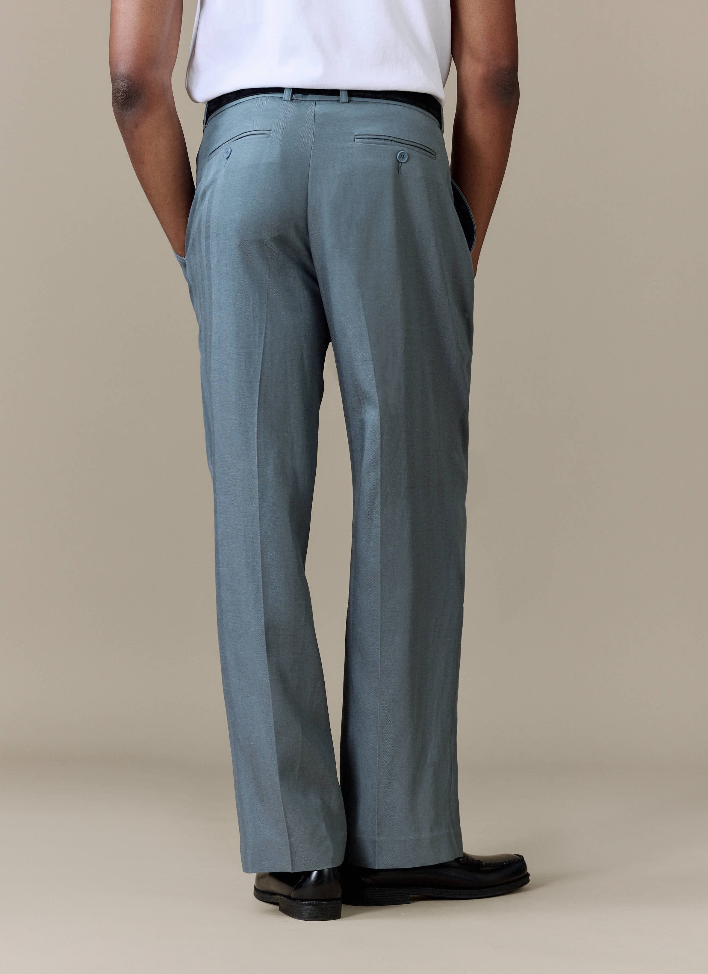 A back view of a model wearing the Percival Pleated Leg Trousers in Slate Blue, showcasing the relaxed fit.