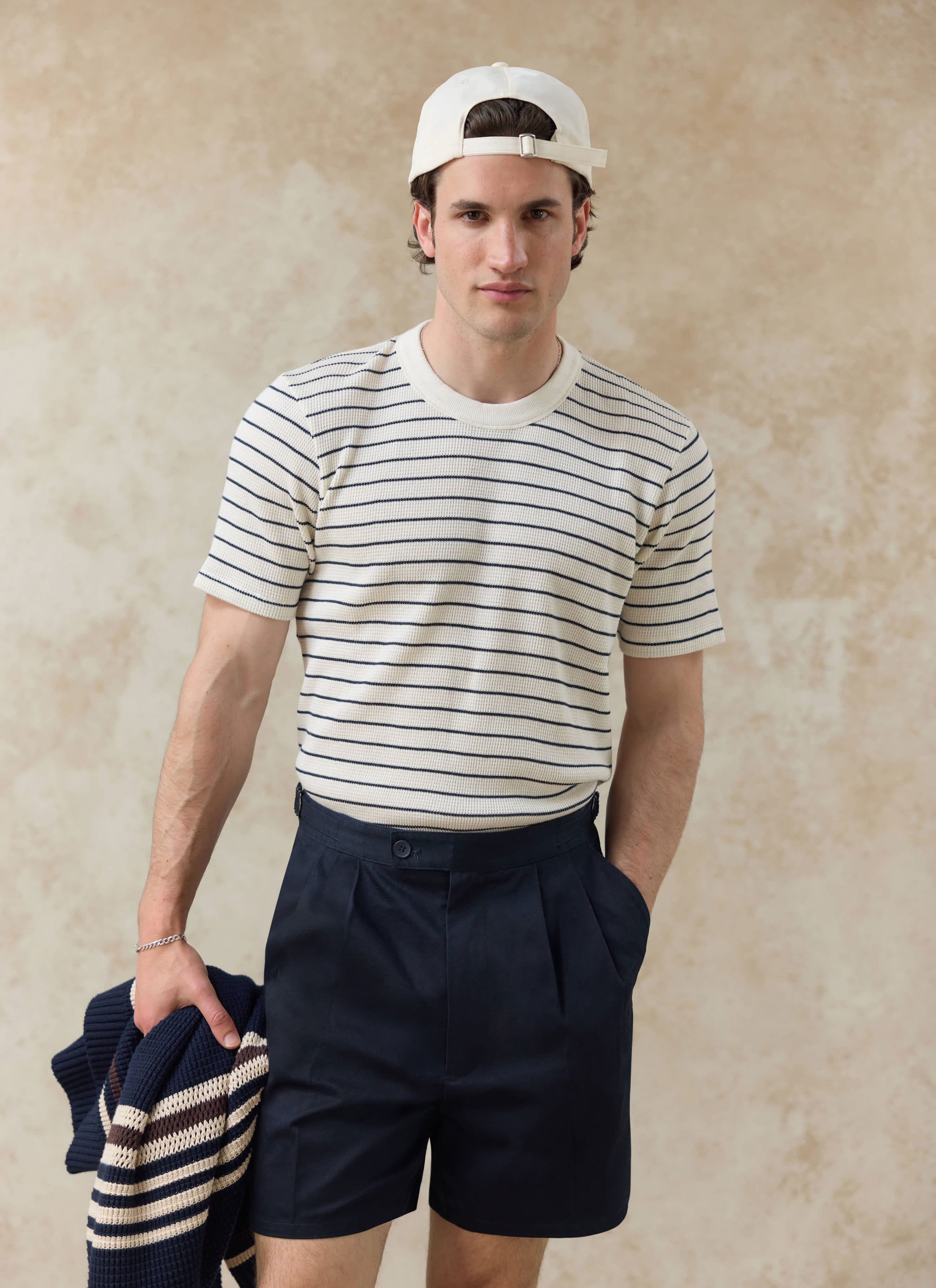 A Percival model wears the cream stripe Ernie waffle t-shirt and navy Blake double pleated cotton shorts.