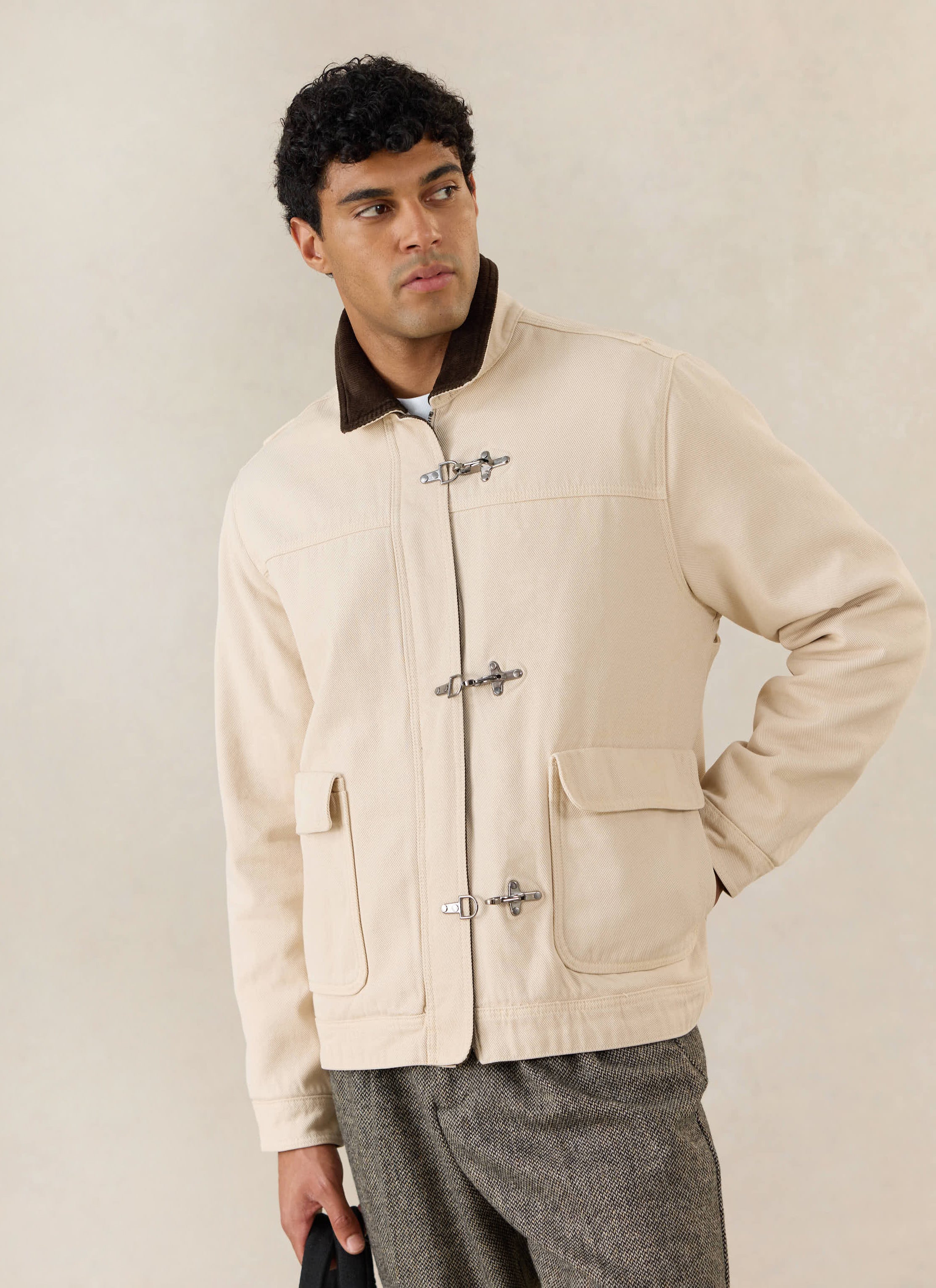 A model wears the cream Percival Fontane cotton jacket with metal clasp closures and a brown corduroy collar.
