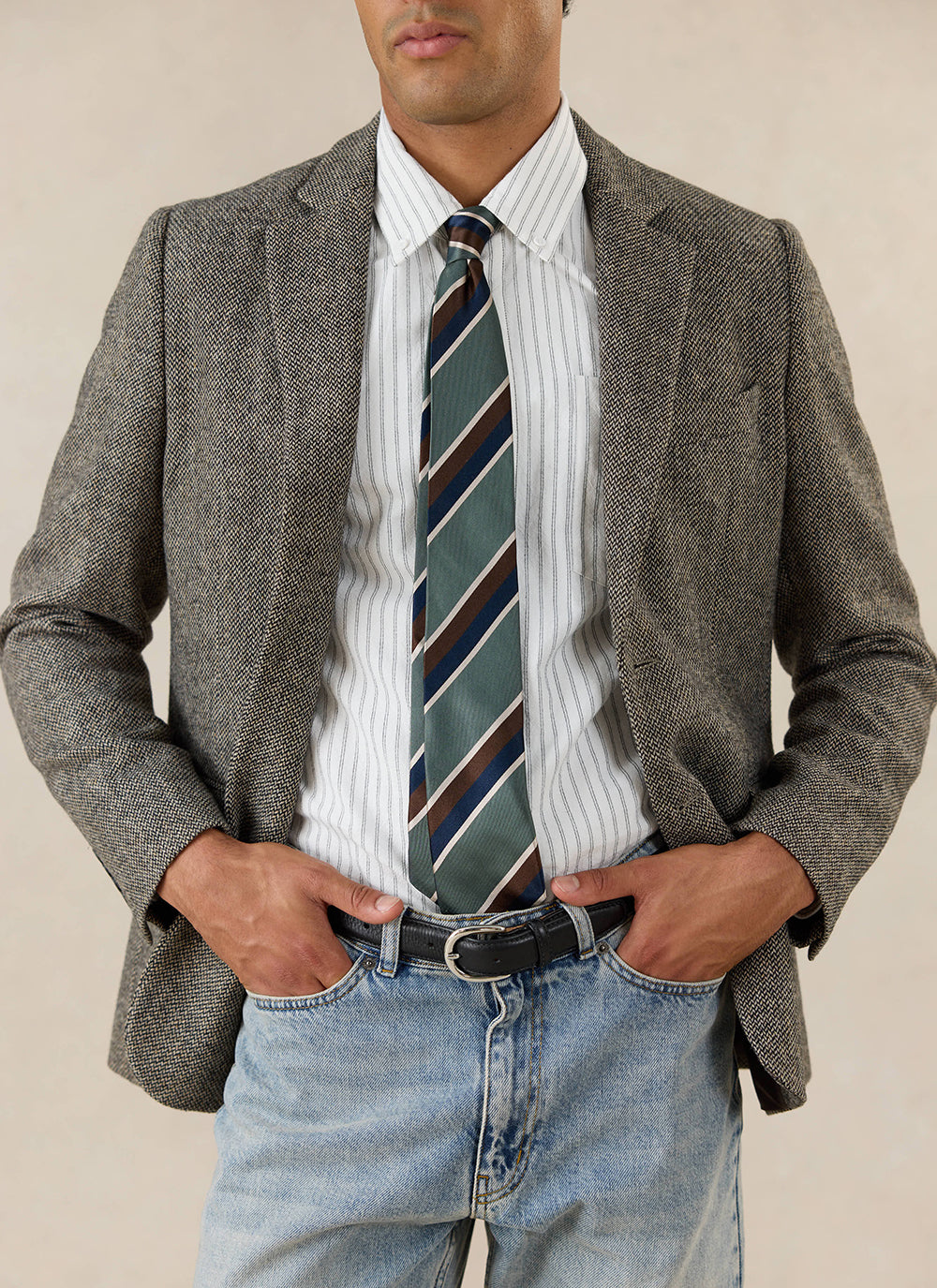 A model wears the Percival Wilde Tailored Blazer in grey birdseye wool, styled with a striped shirt and green tie.