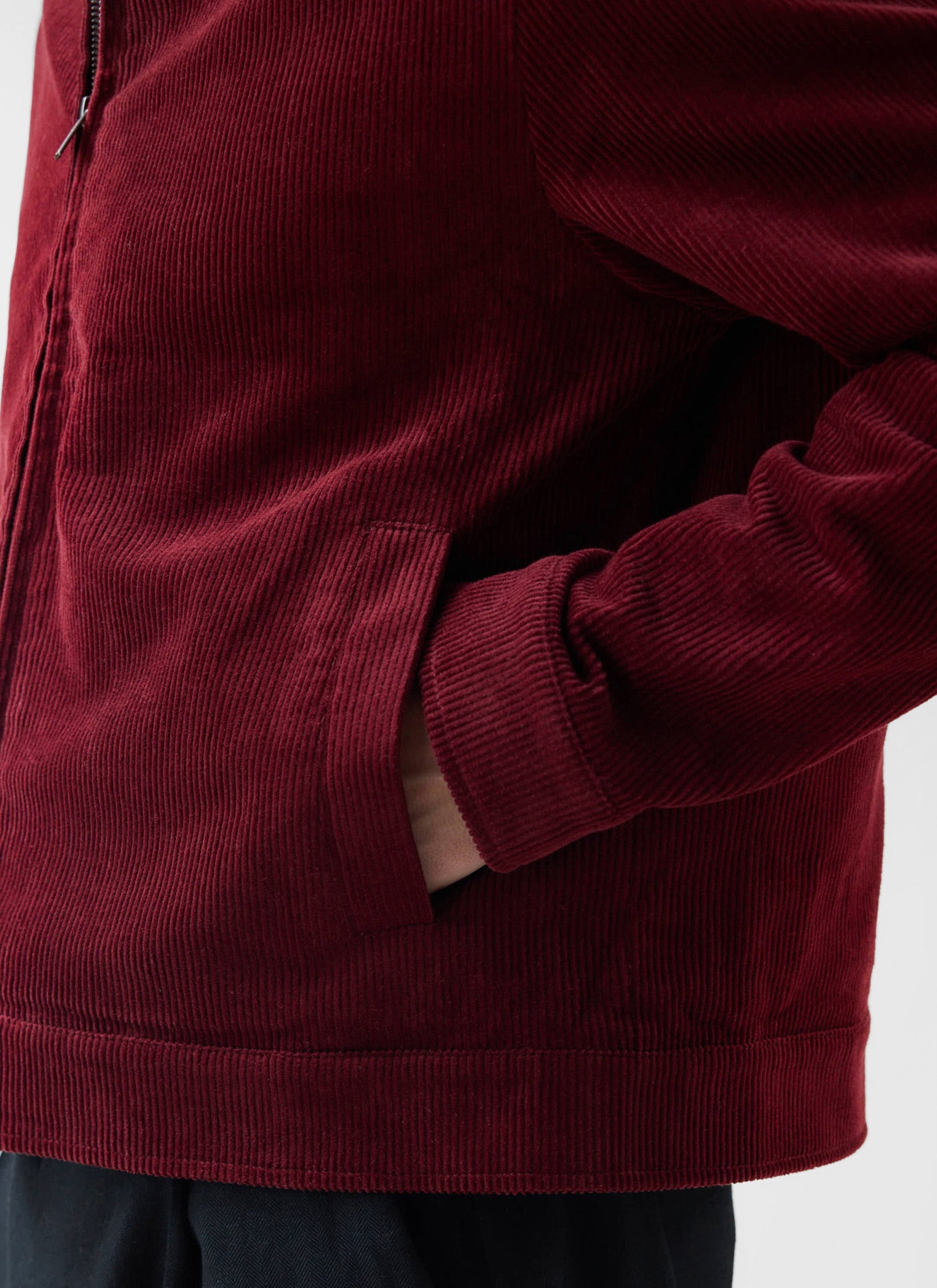 A detailed shot of the burgundy Marcel Cord Jacket from Percival, hand in pocket, highlighting its deep wale corduroy.