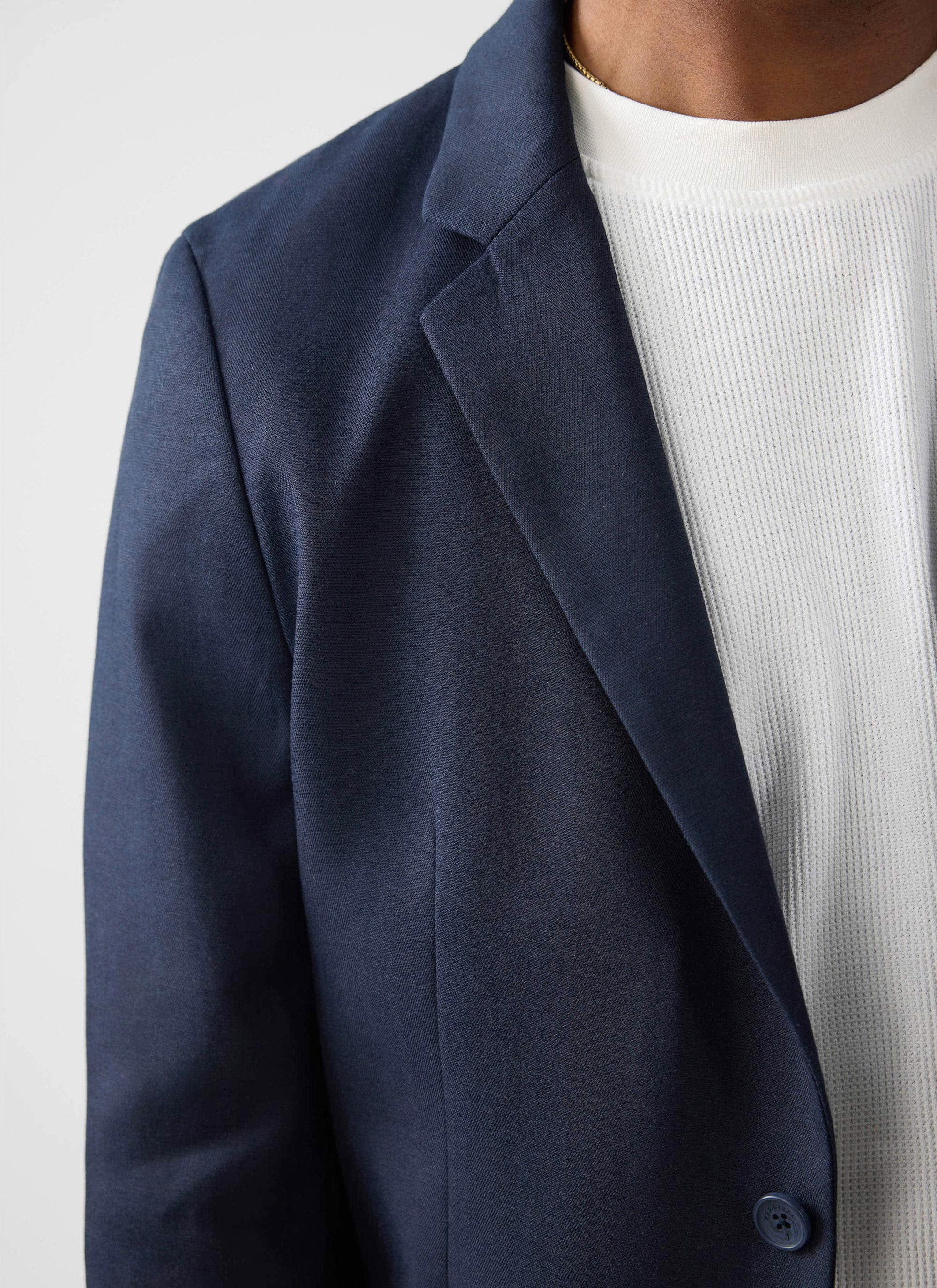 Close-up of a model wearing the navy Lyocell Regular Blazer from Percival, layered over a white waffle-knit t-shirt.