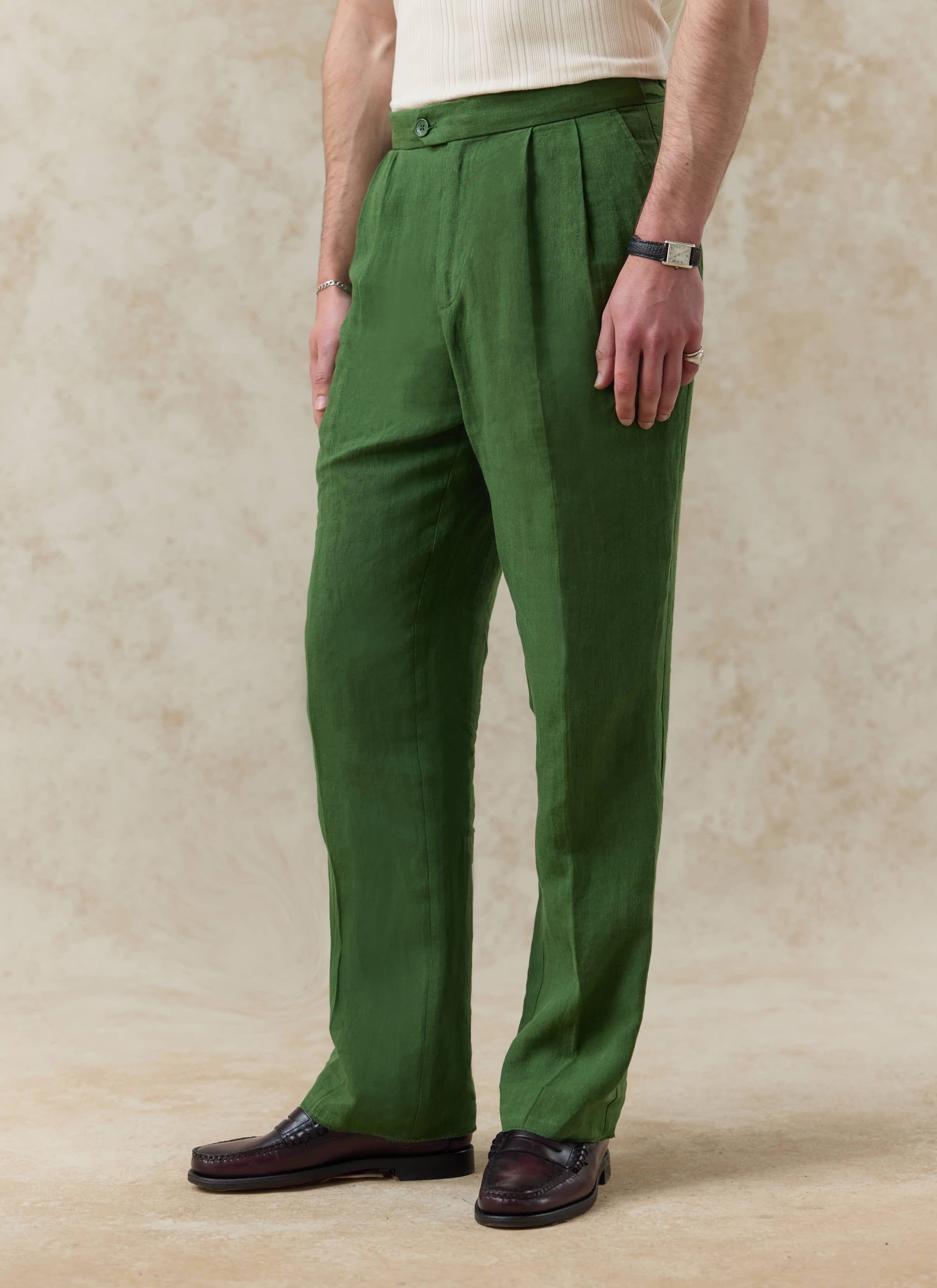 Forest green pleated linen tailored trousers by Percival, featuring a relaxed fit and double pleat detail.