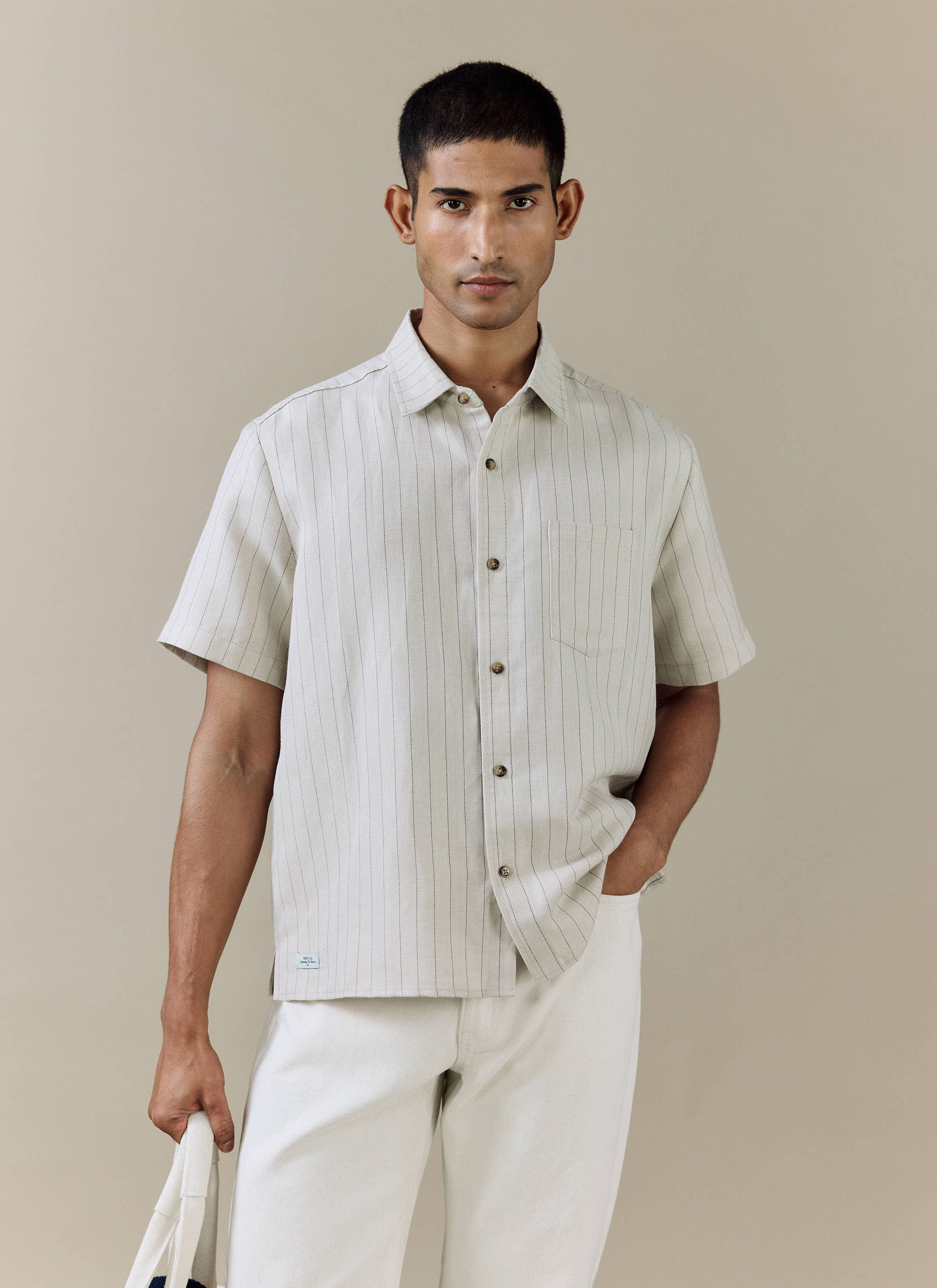 Model wears the Percival Striped Boxy Shirt in cream linen blend, featuring subtle pinstripes and a herringbone weave.