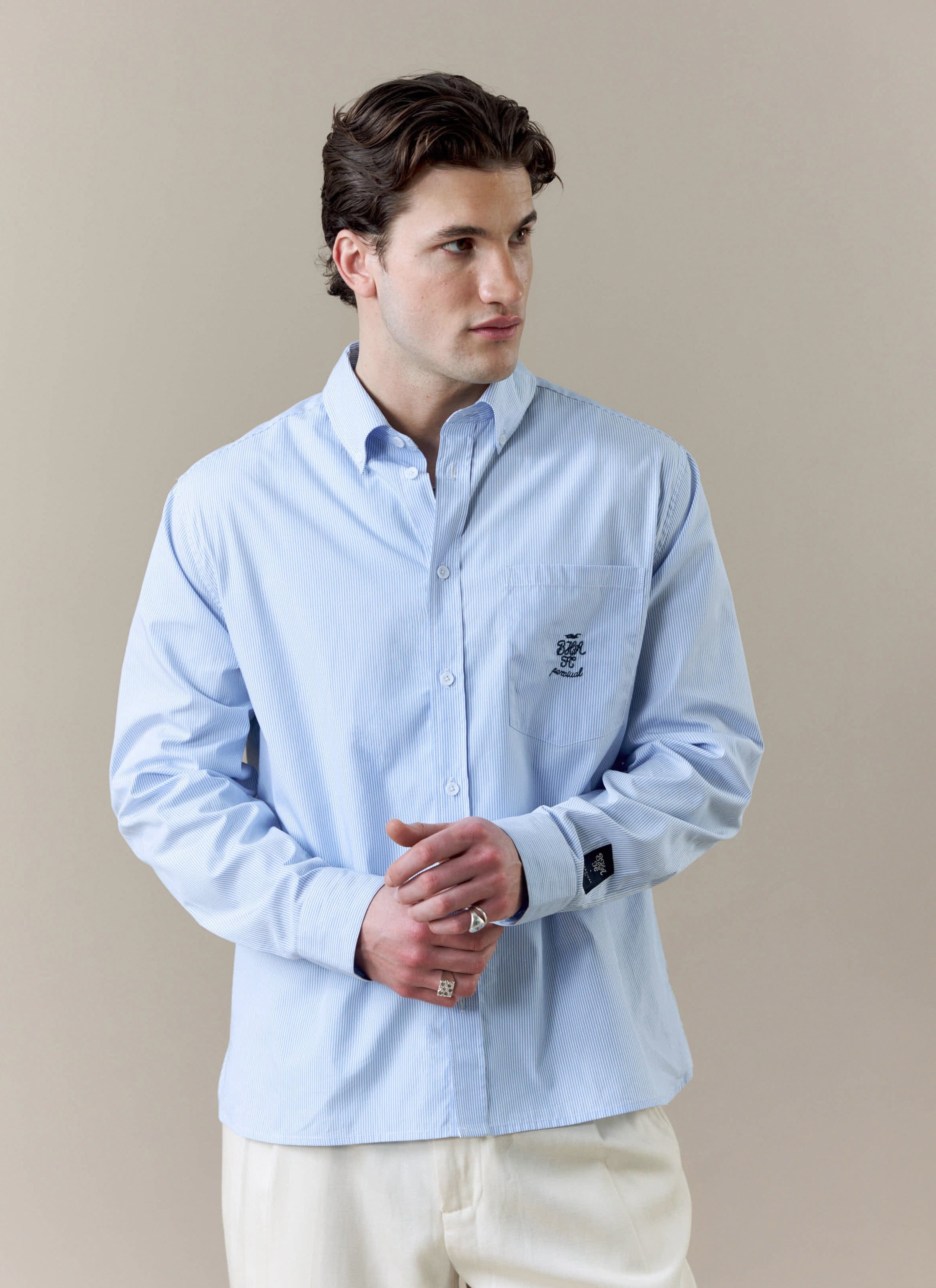 A model wears the light blue and white striped Pearce shirt from the Percival x Brighton & Hove Albion F.C. collaboration.