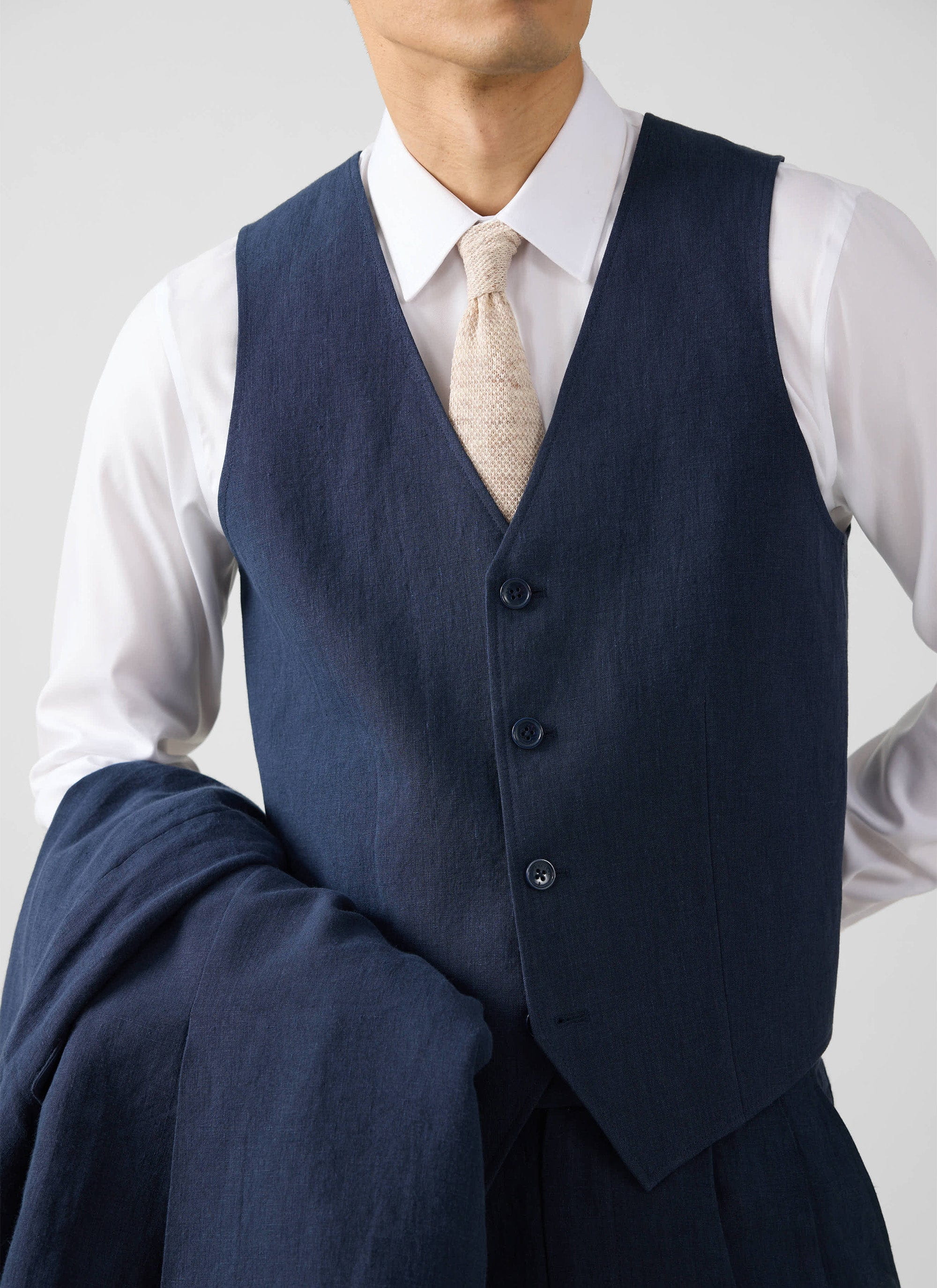 A close-up of a model wearing the Percival navy linen waistcoat over a crisp white shirt, with a matching blazer.
