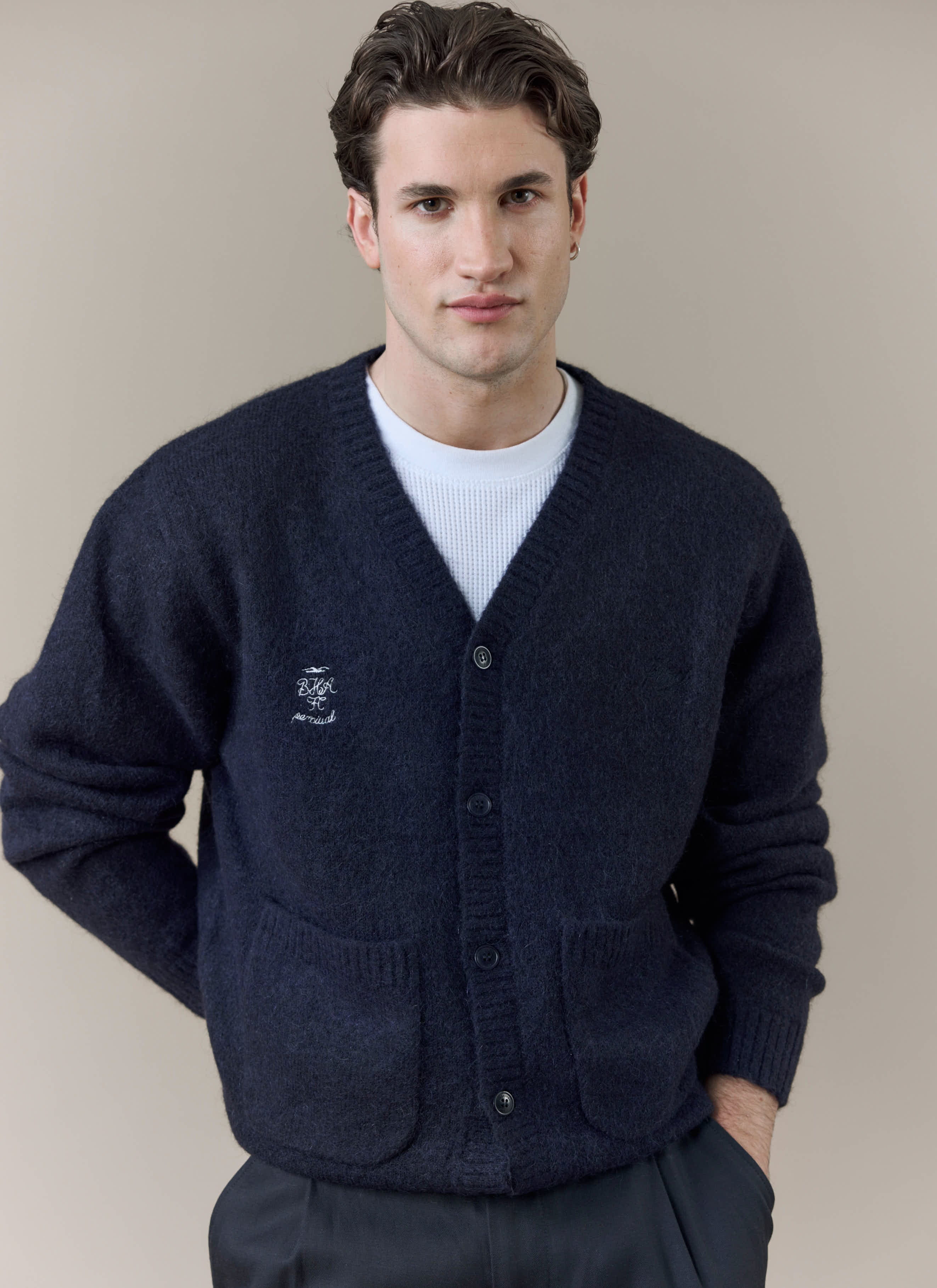 A model wears the navy wool-blend White Glove Cardigan from the Percival x Brighton & Hove Albion F.C. collaboration.