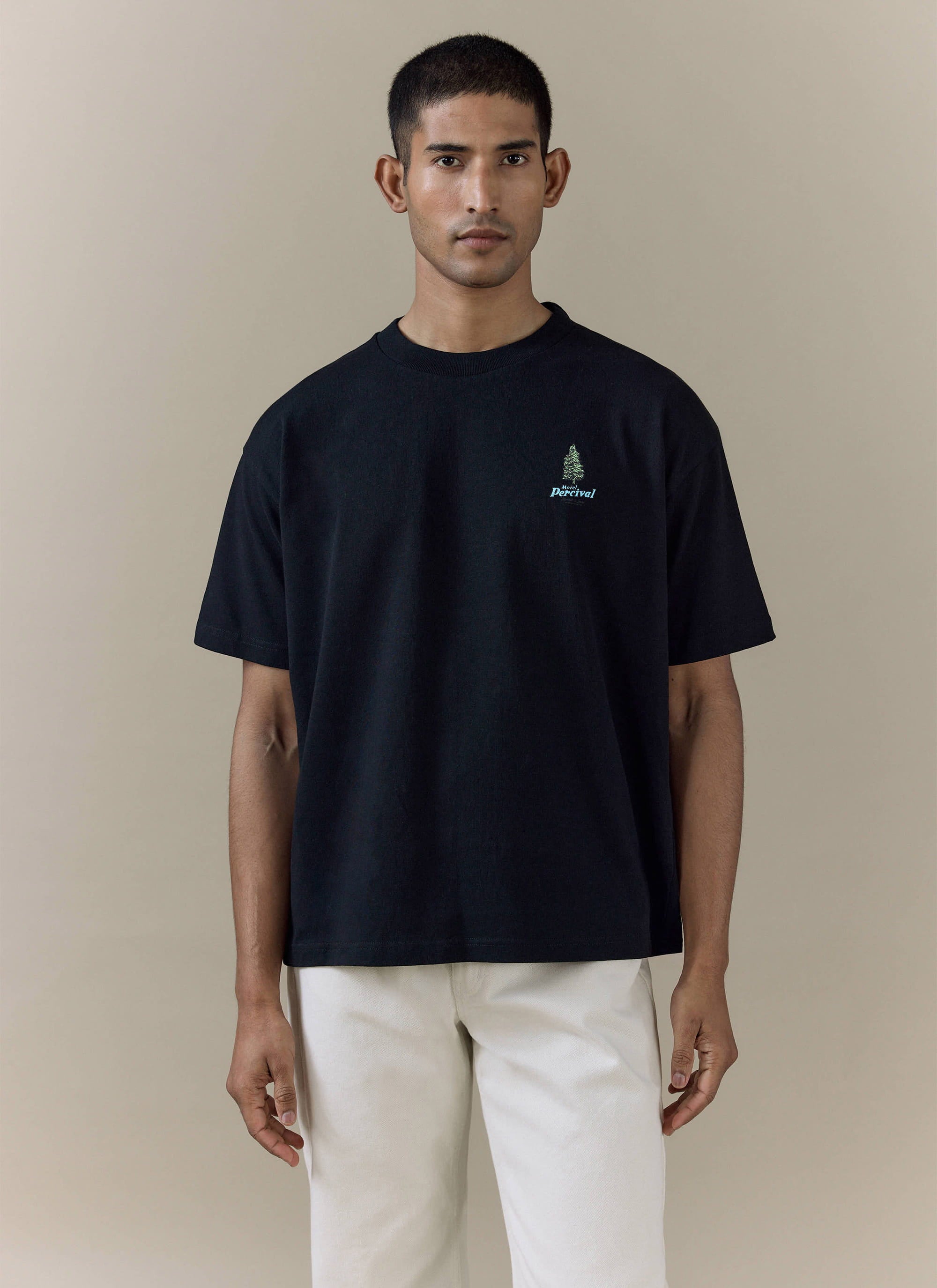Percival Arnold Oversized T Shirt in black organic cotton with a green tree chest embroidery, worn by a male model.