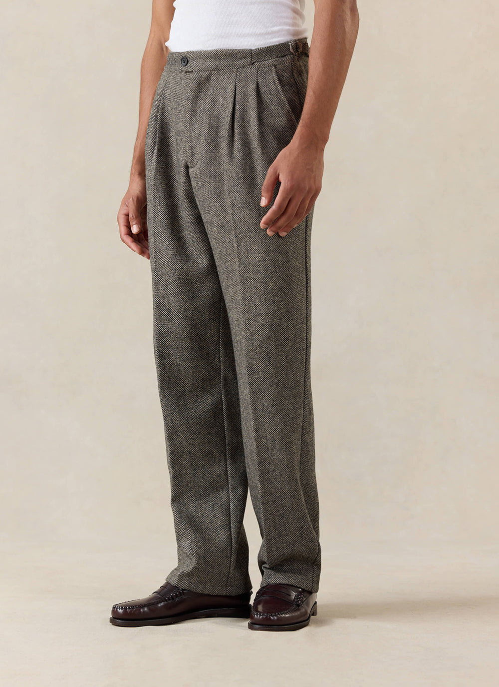 A model wears the Percival Blake Double Pleated Tailored Trousers in grey birdseye wool.