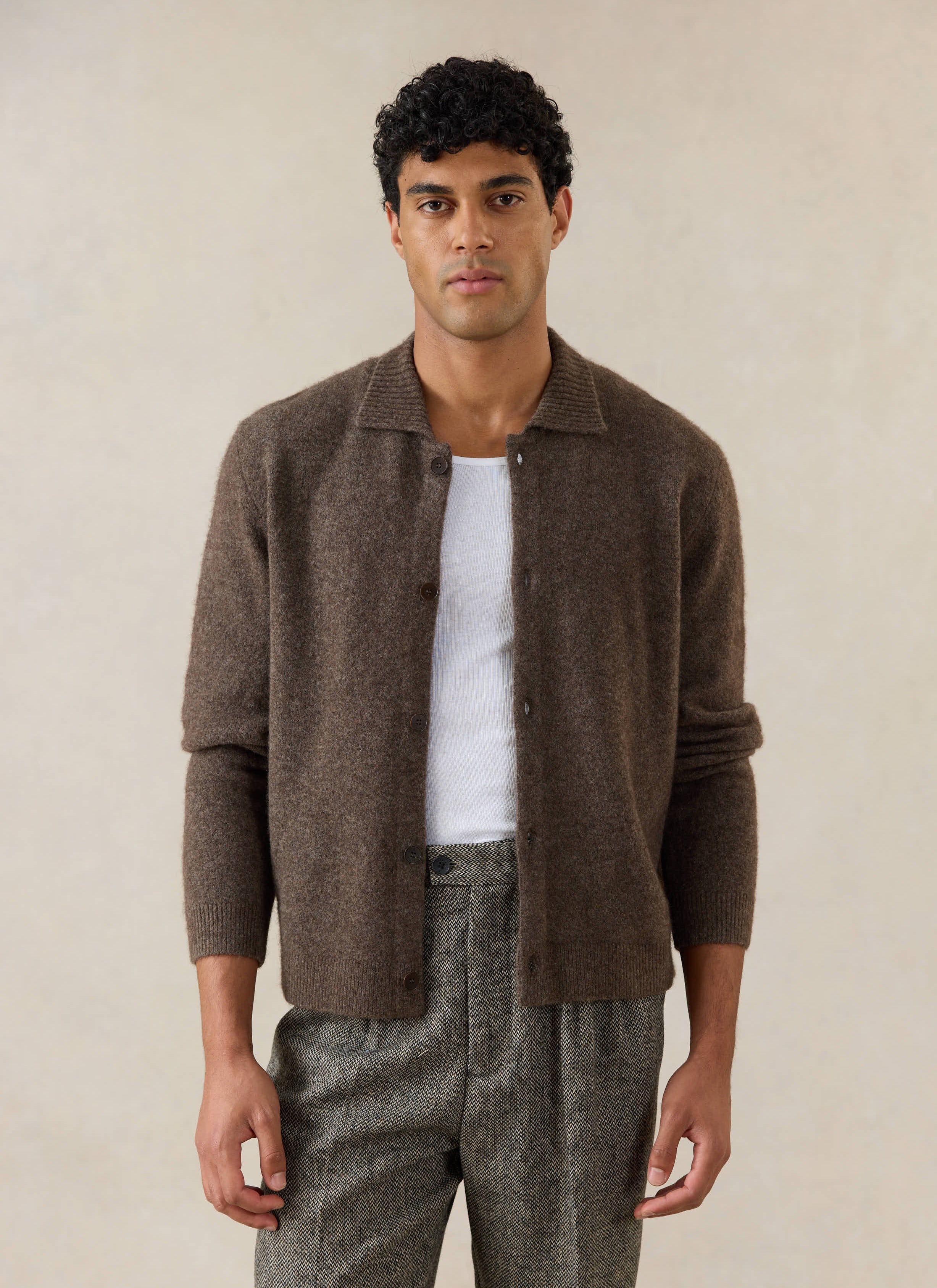 A model wears the brown Percival Archive Knit Collared Cardigan in yak wool, styled with a white vest and textured trousers.