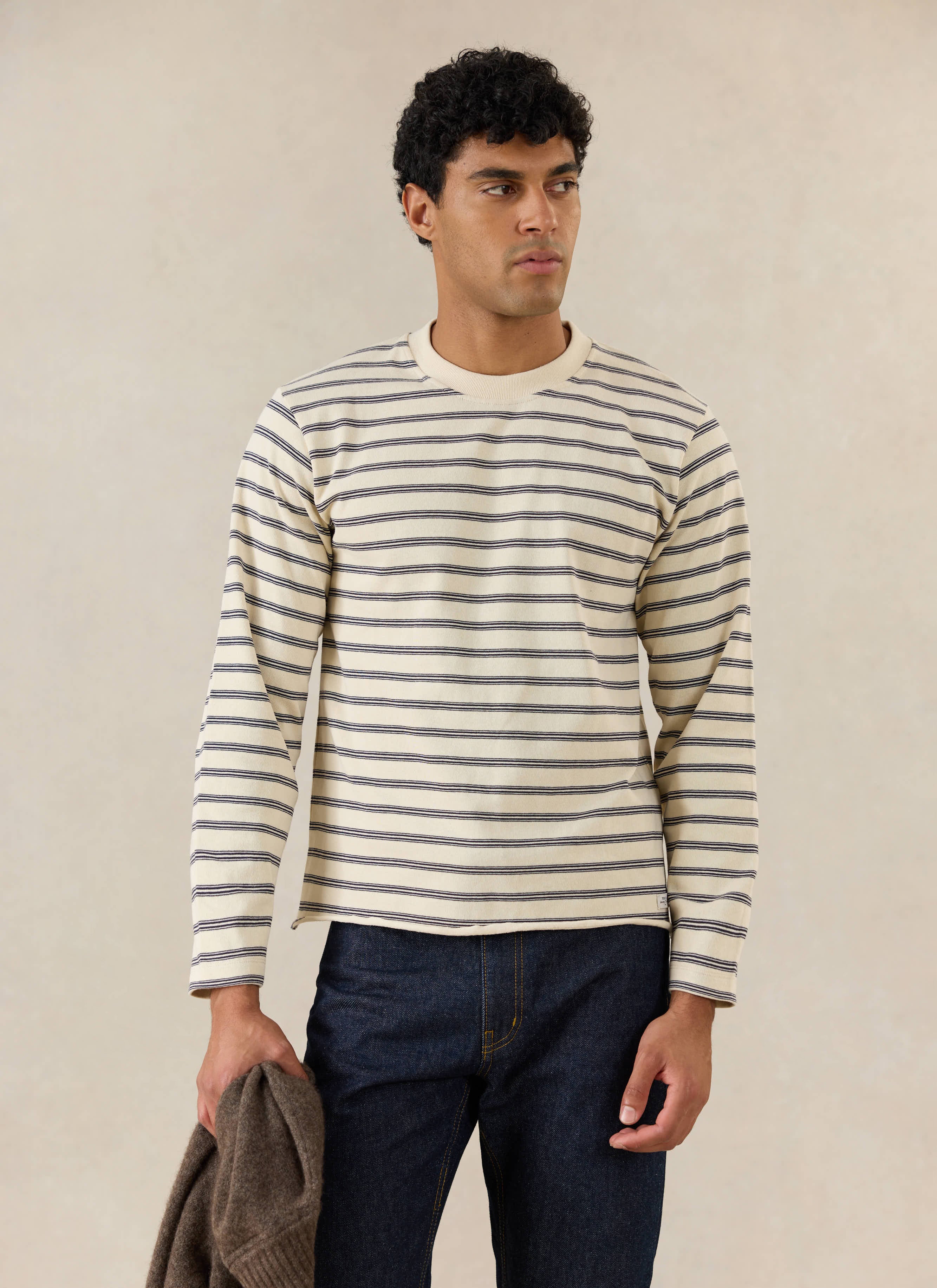 A model wears the white stripe Percival Arlo organic cotton Breton t-shirt with a raw hem, styled with dark denim jeans.
