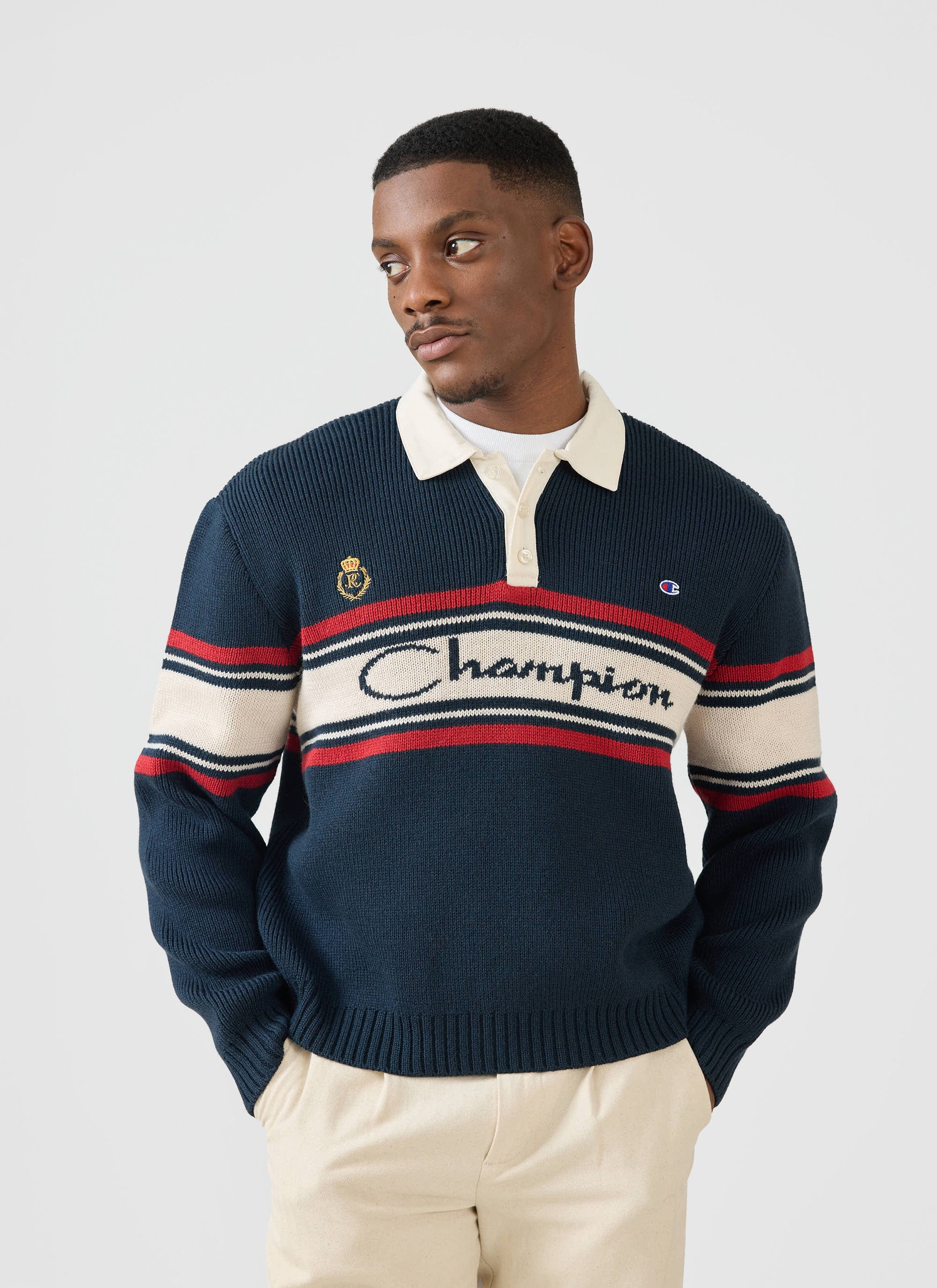 A man models the navy wool-blend Jacquard Knitted Rugby Polo Shirt from the Champion x Percival collaboration.