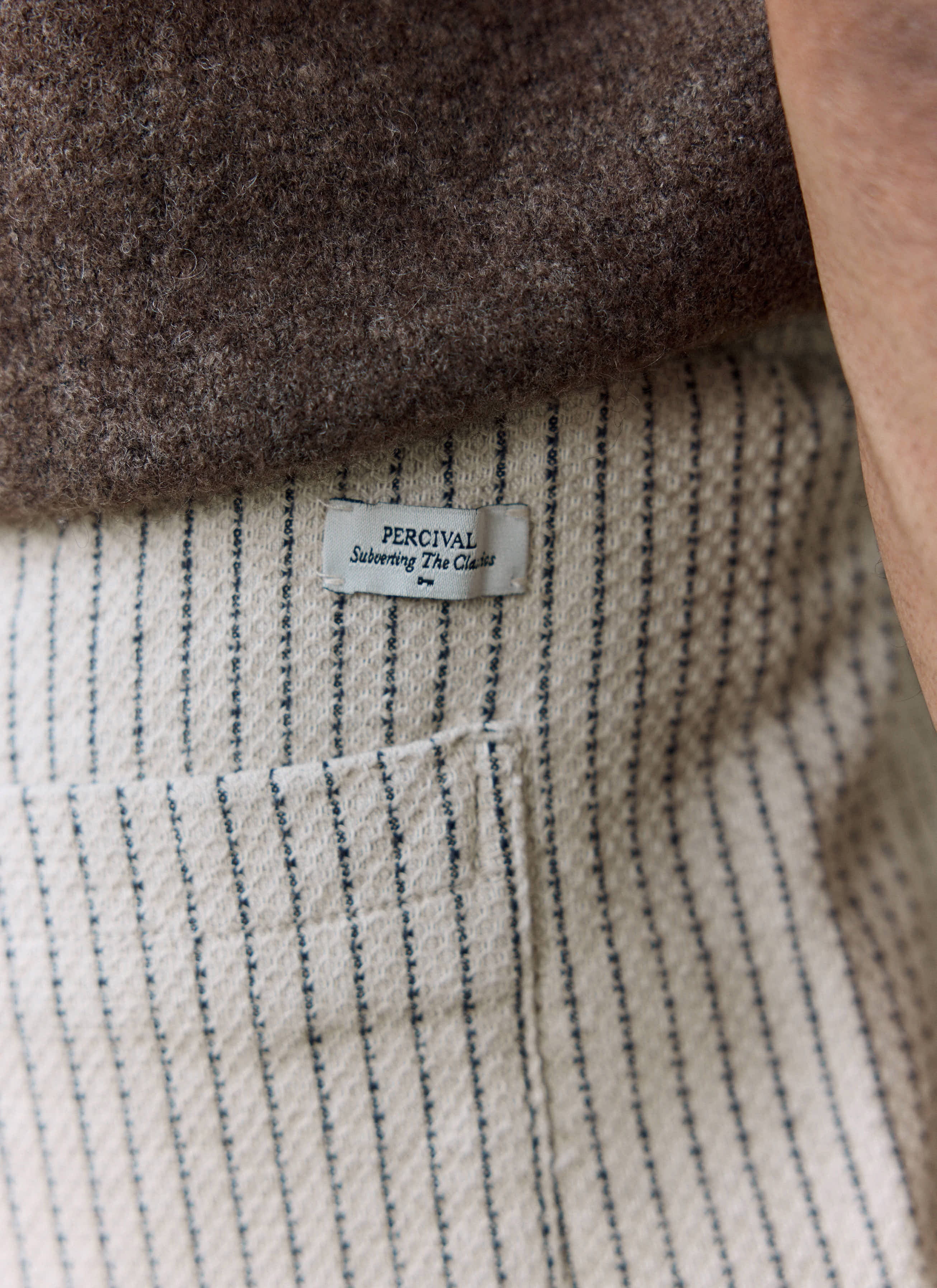 A detailed close-up of the Percival label on the back pocket of the Sorrento Wide Leg Trousers in ecru linen.