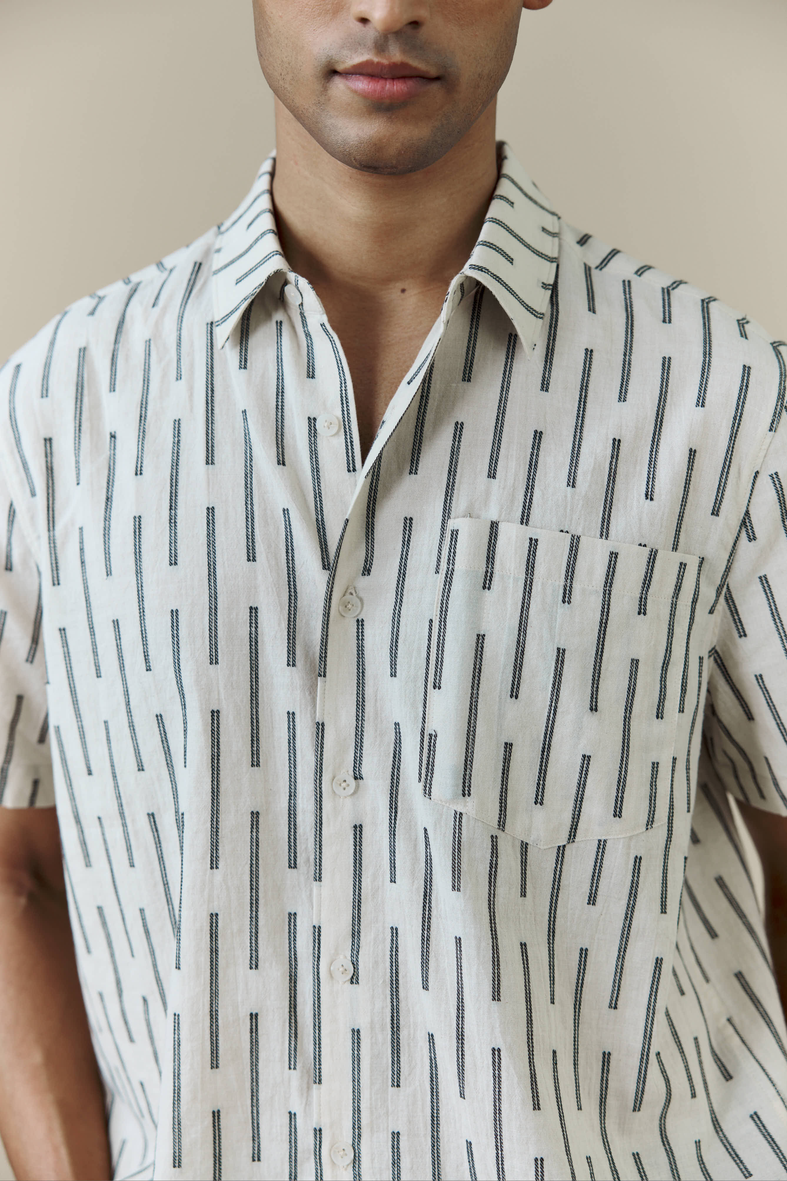 A close-up of the Percival Nancy Boxy Shirt in ecru, showing the black jacquard stripe pattern and chest pocket.