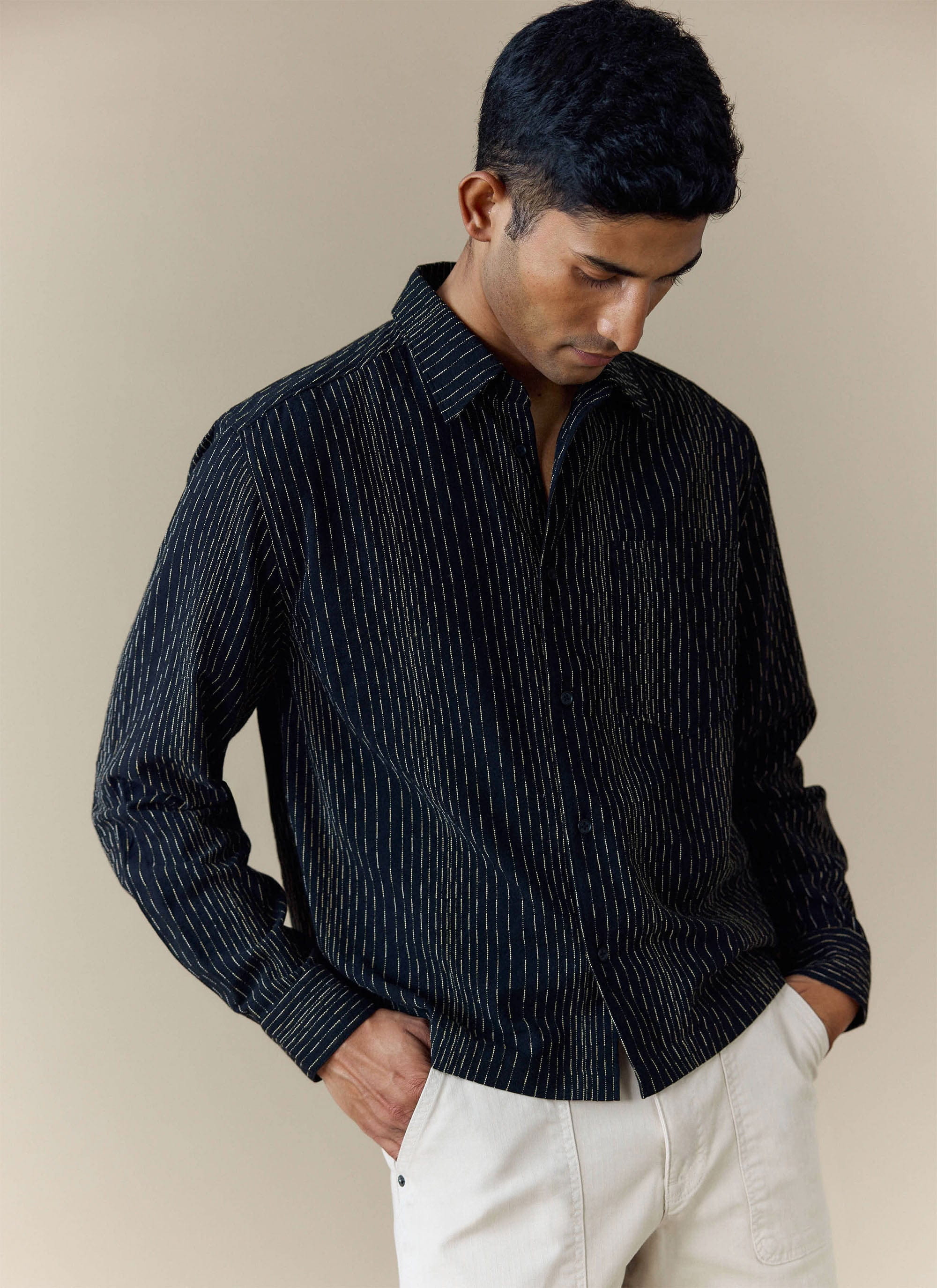 A model wears the black striped Percival Leland Cuban Boxy Shirt, styled with off-white trousers.