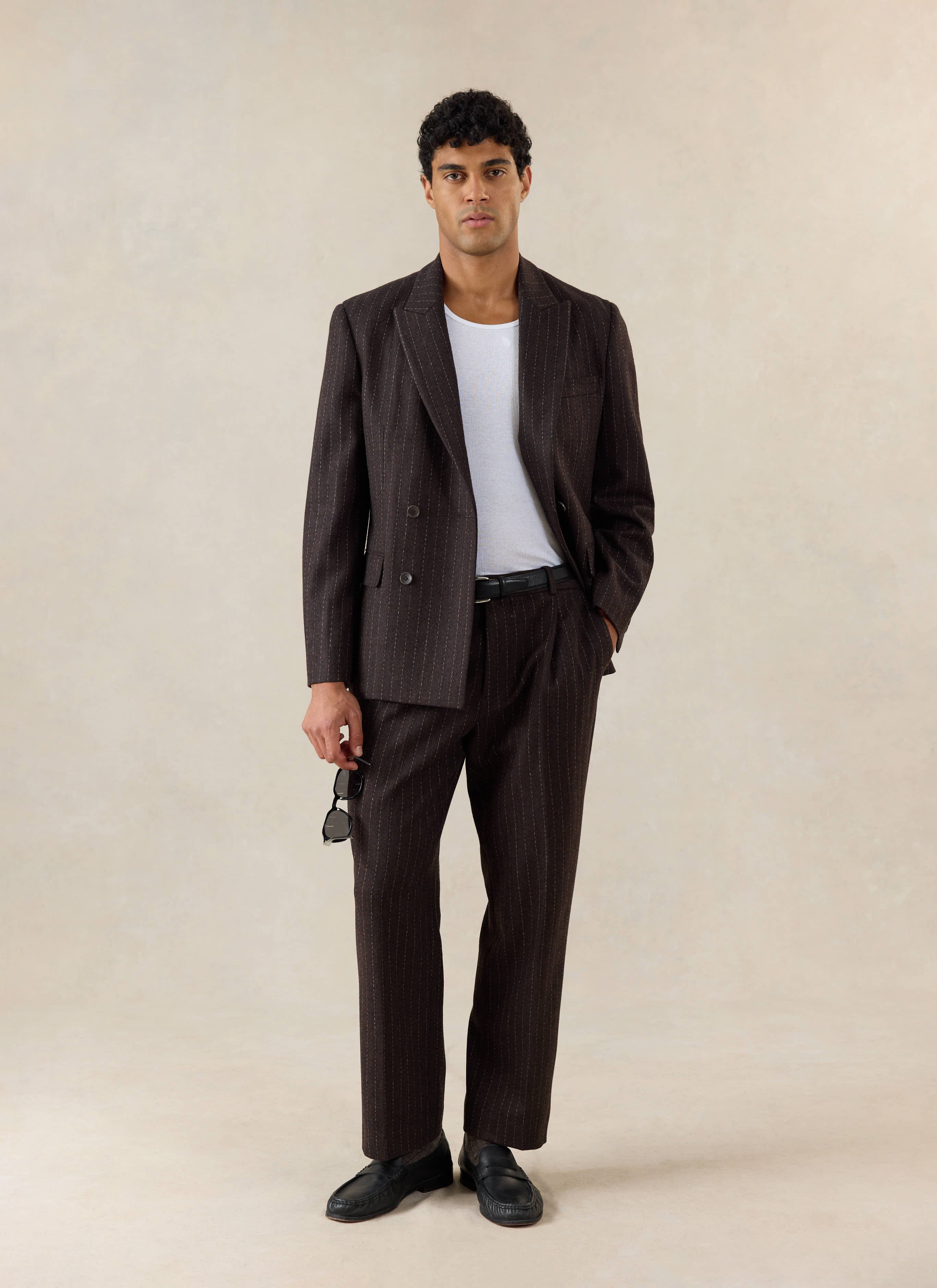 A model wears Percival Clifton Pinstripe Double Breasted Blazer and Clifton Pinstripe Pleated Tailored Trousers in Espresso.
