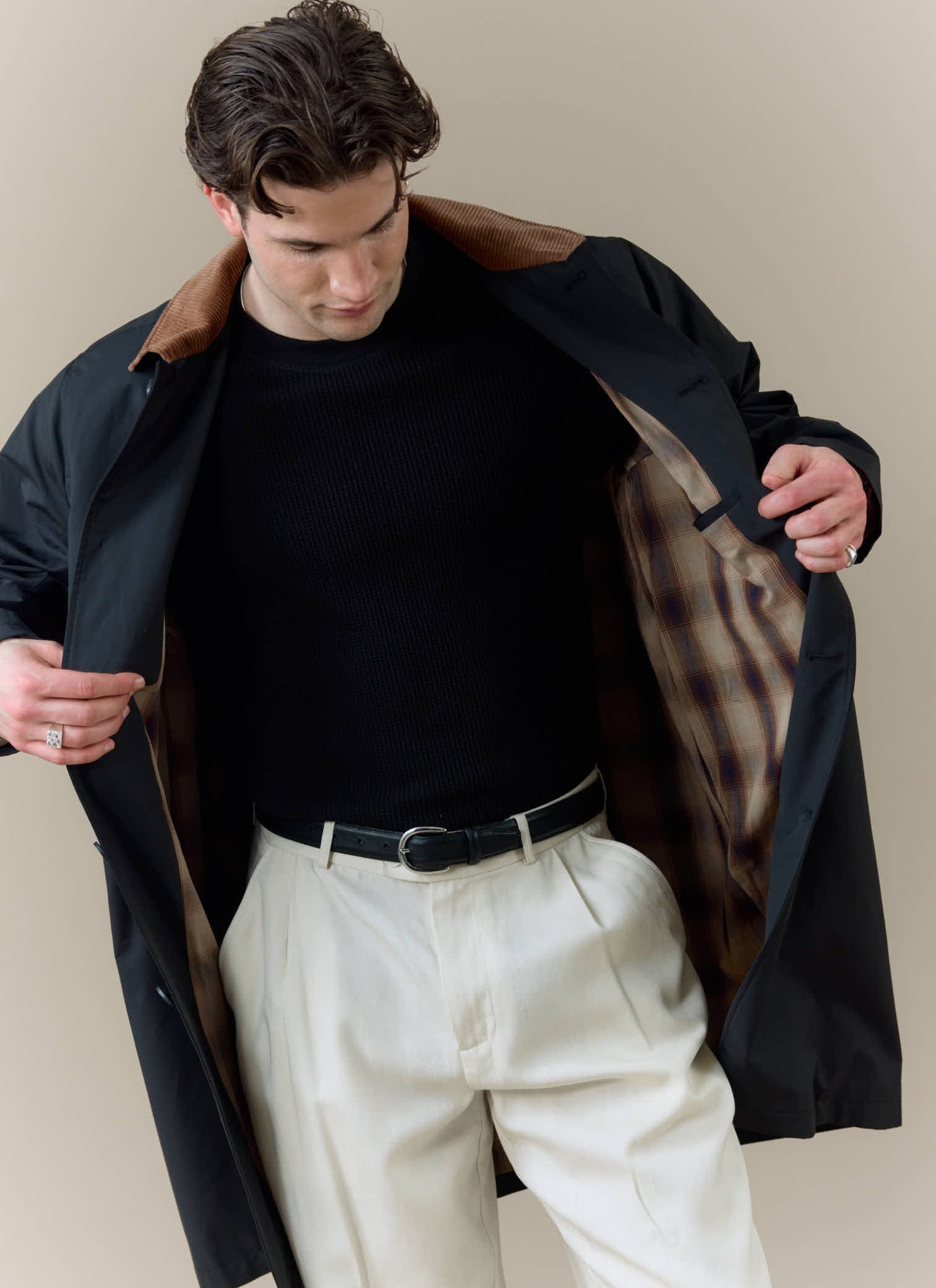 A model wearing the black Percival Mac Cord Collar Coat, showing the contrast corduroy collar and checked internal lining.
