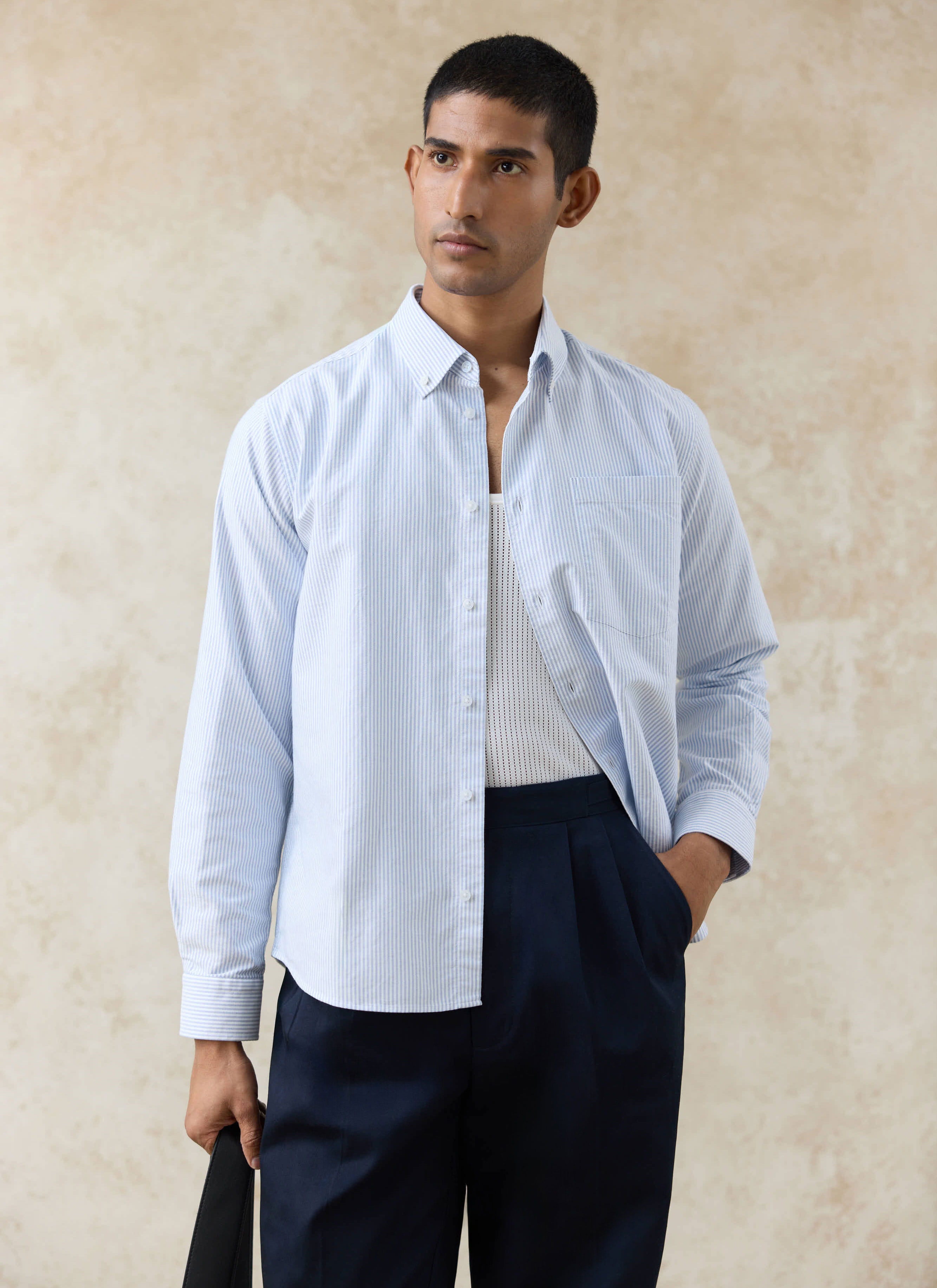 Percival blue striped cotton Oxford regular shirt with a button-down collar, worn over a white vest and navy trousers.
