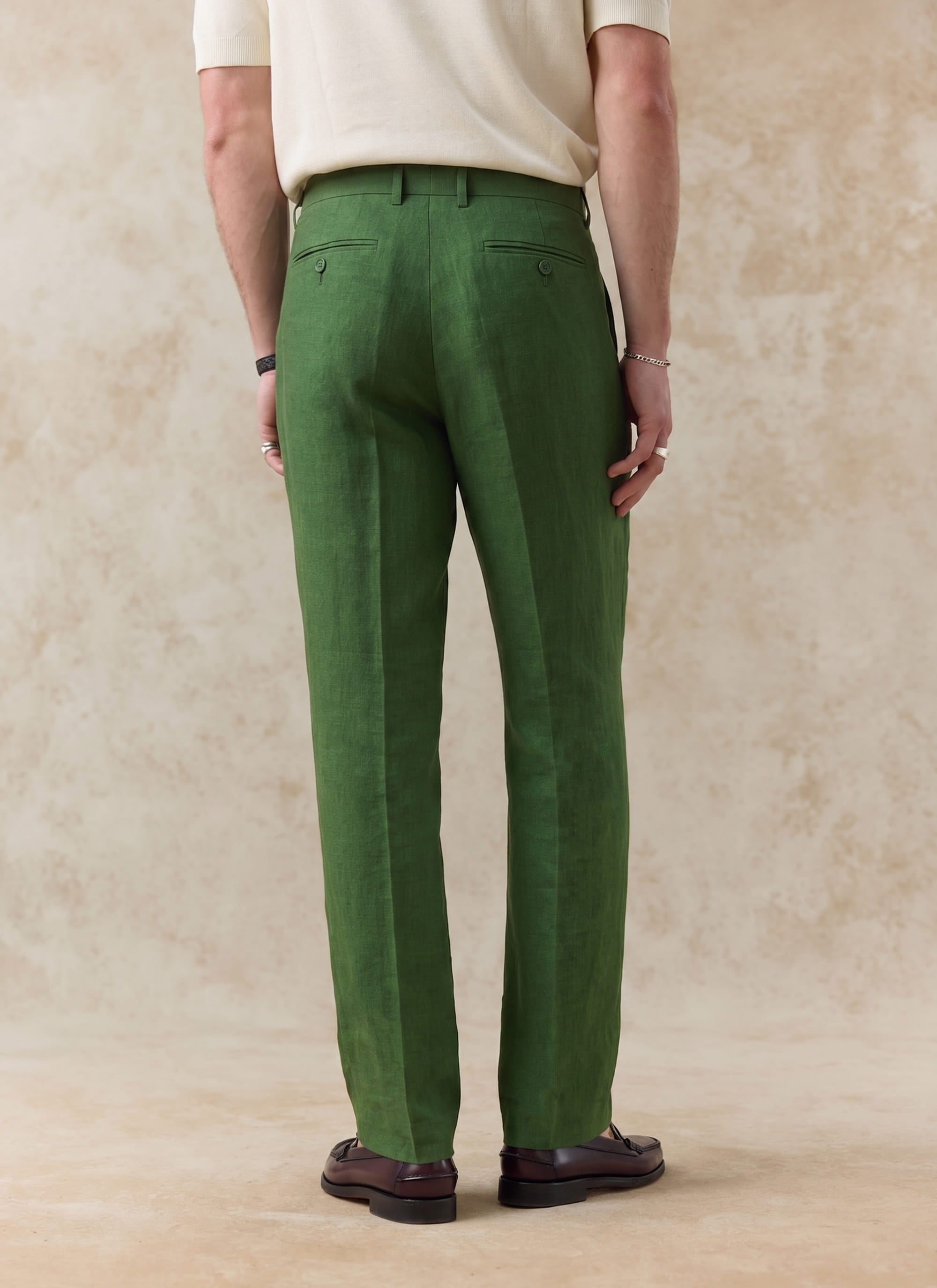 Rear view of Percival's forest green tailored linen trousers, showing the straight leg fit and buttoned back welt pockets.