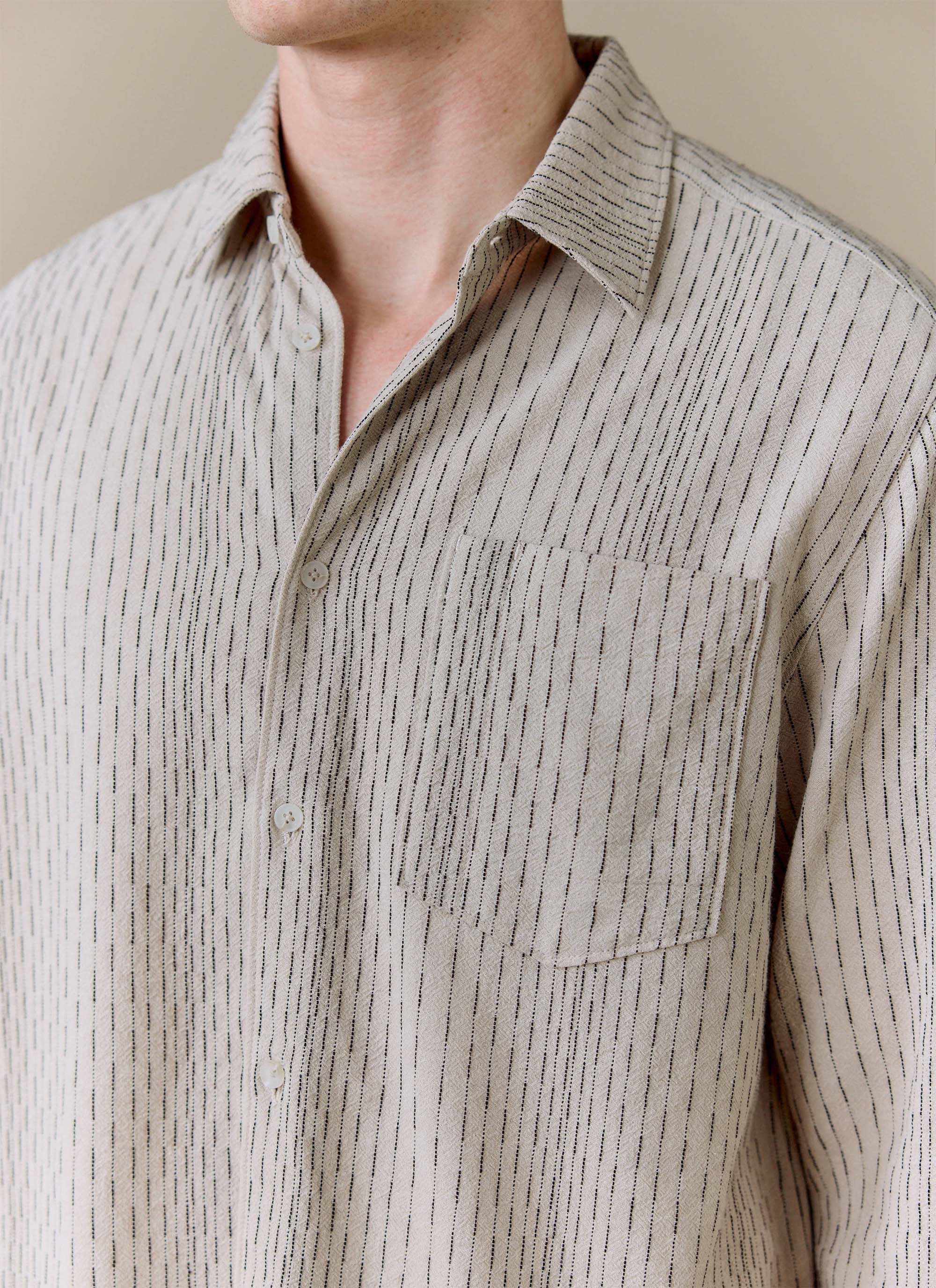 A detailed close-up of the Percival Leland Cuban Boxy Shirt in ecru, showing the striped cotton fabric and chest pocket.