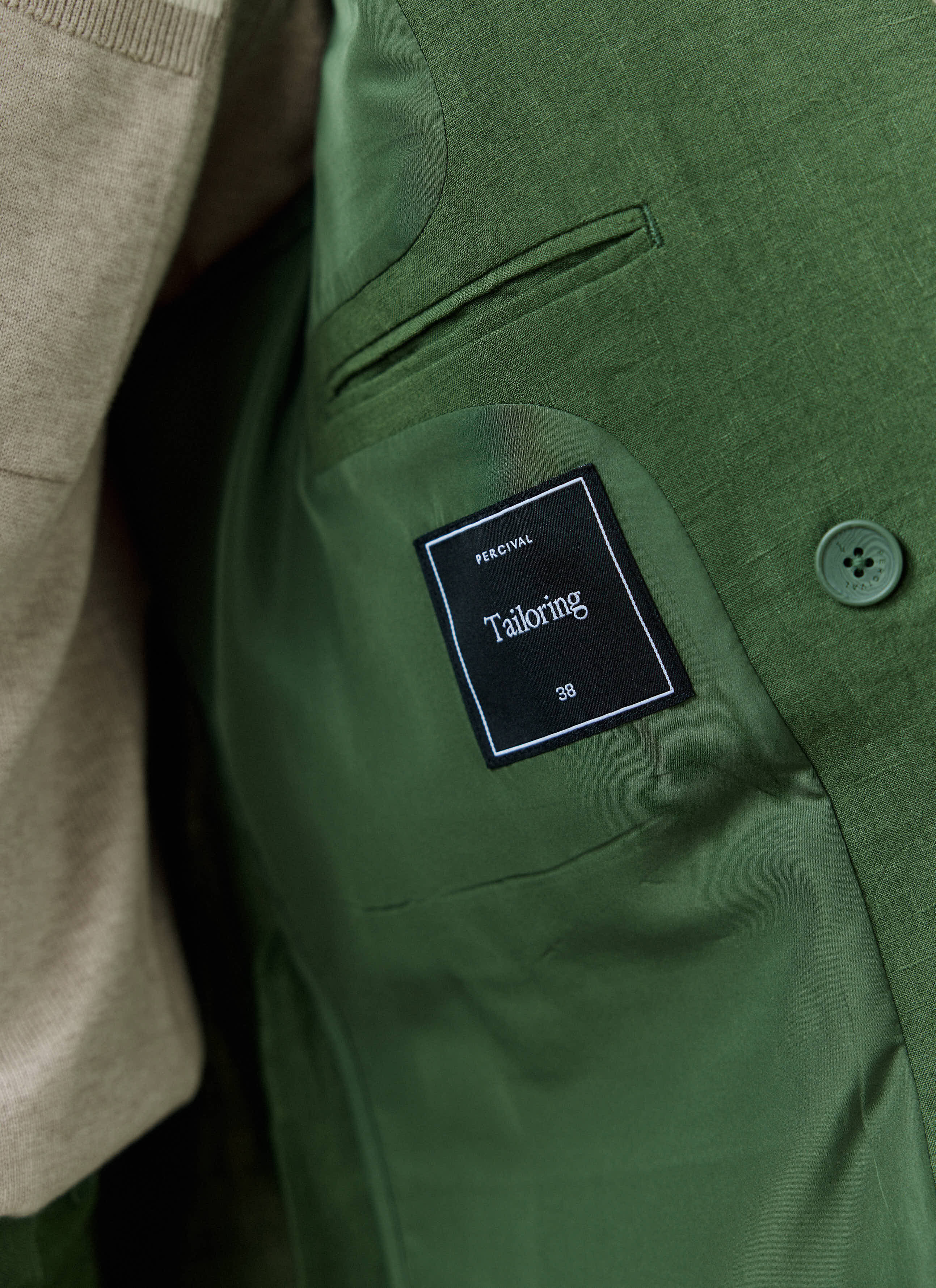 Inside of the Percival Clifton blazer in forest green linen, showing the black tailoring label and internal pocket.