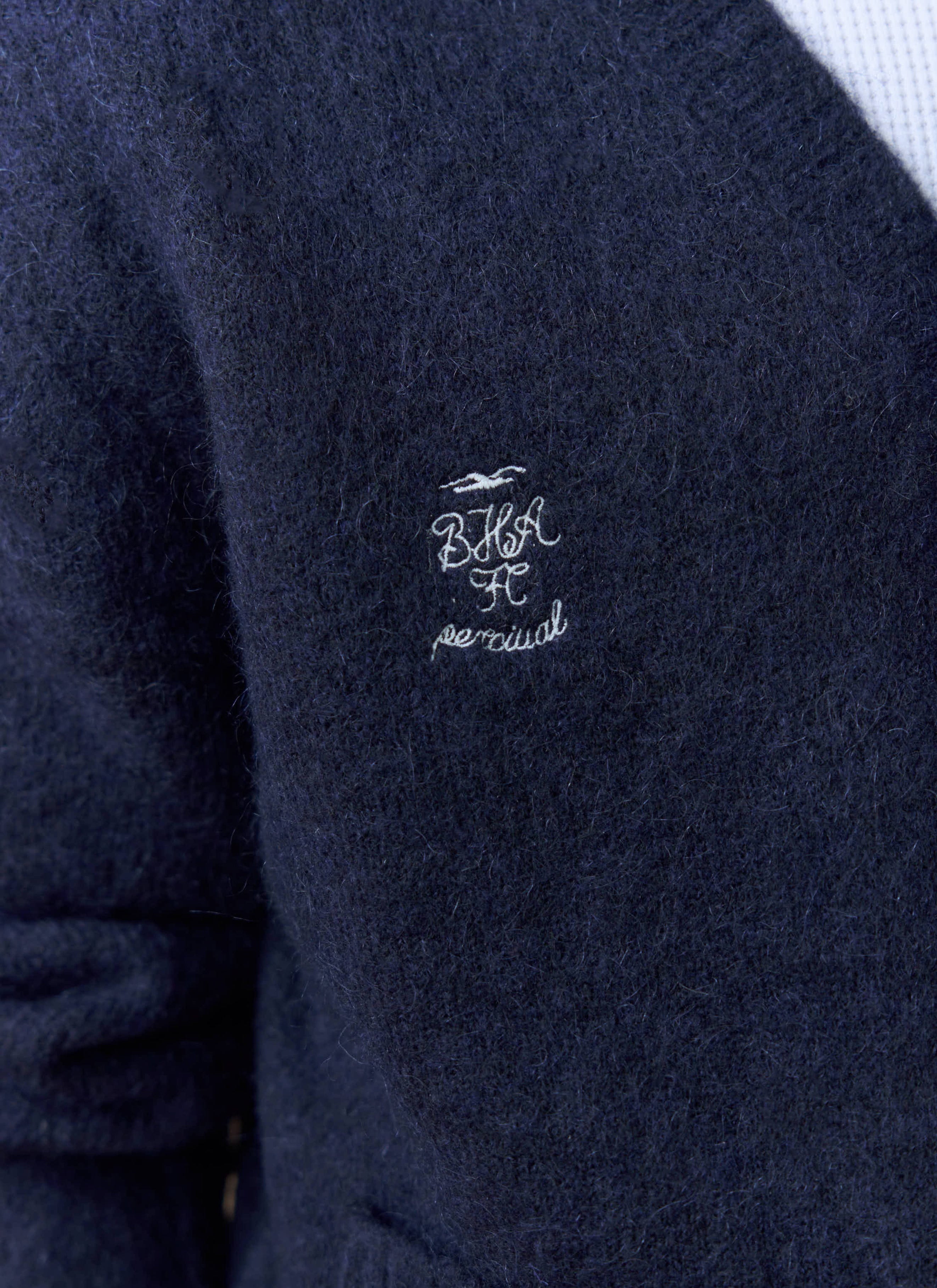 A close-up of the embroidered Percival x Brighton & Hove Albion F.C. logo on the chest of the navy White Glove Cardigan.