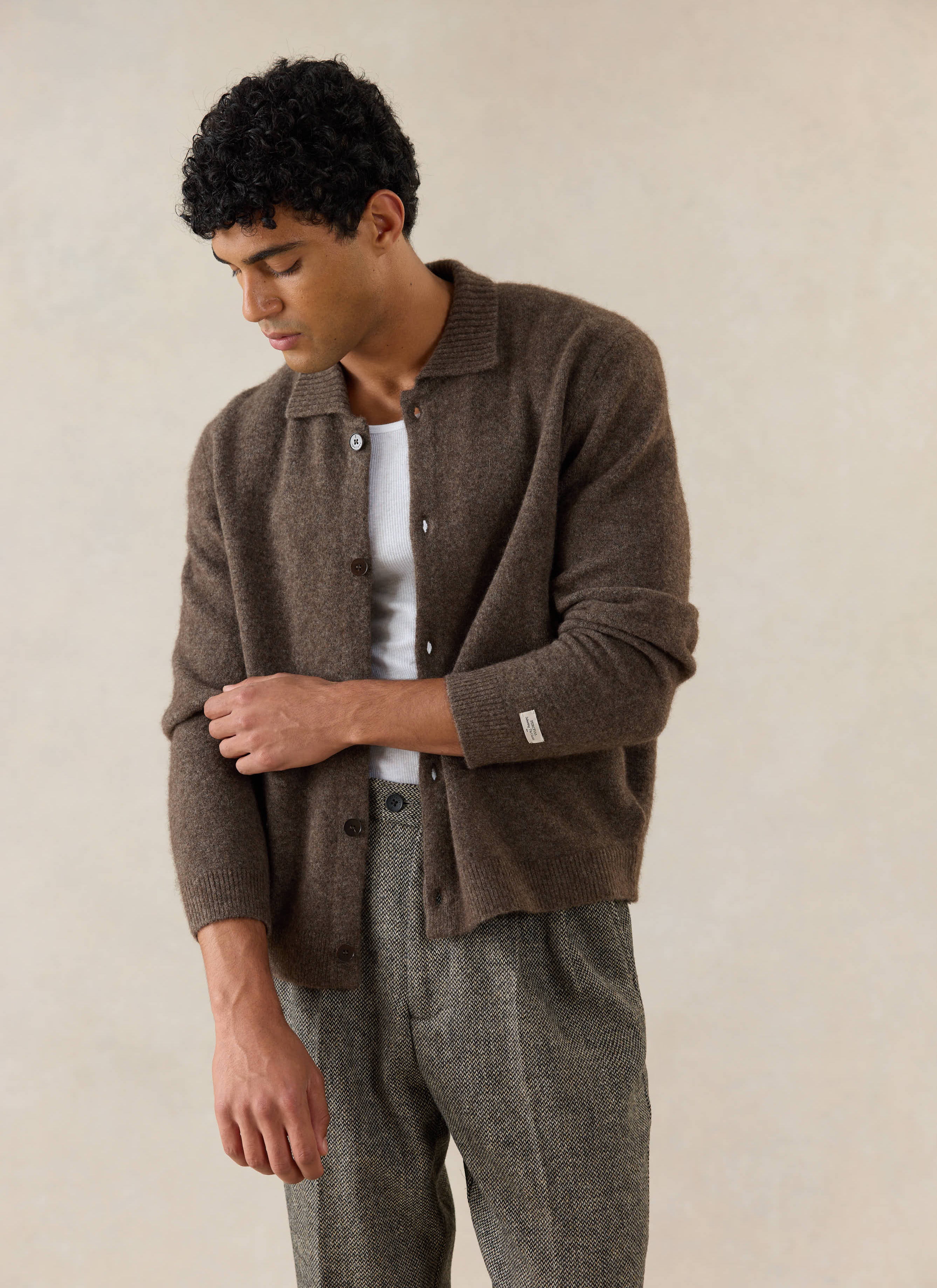 A model wears the brown Percival Archive Knit Collared Cardigan in yak wool, styled with a white vest and patterned trousers.
