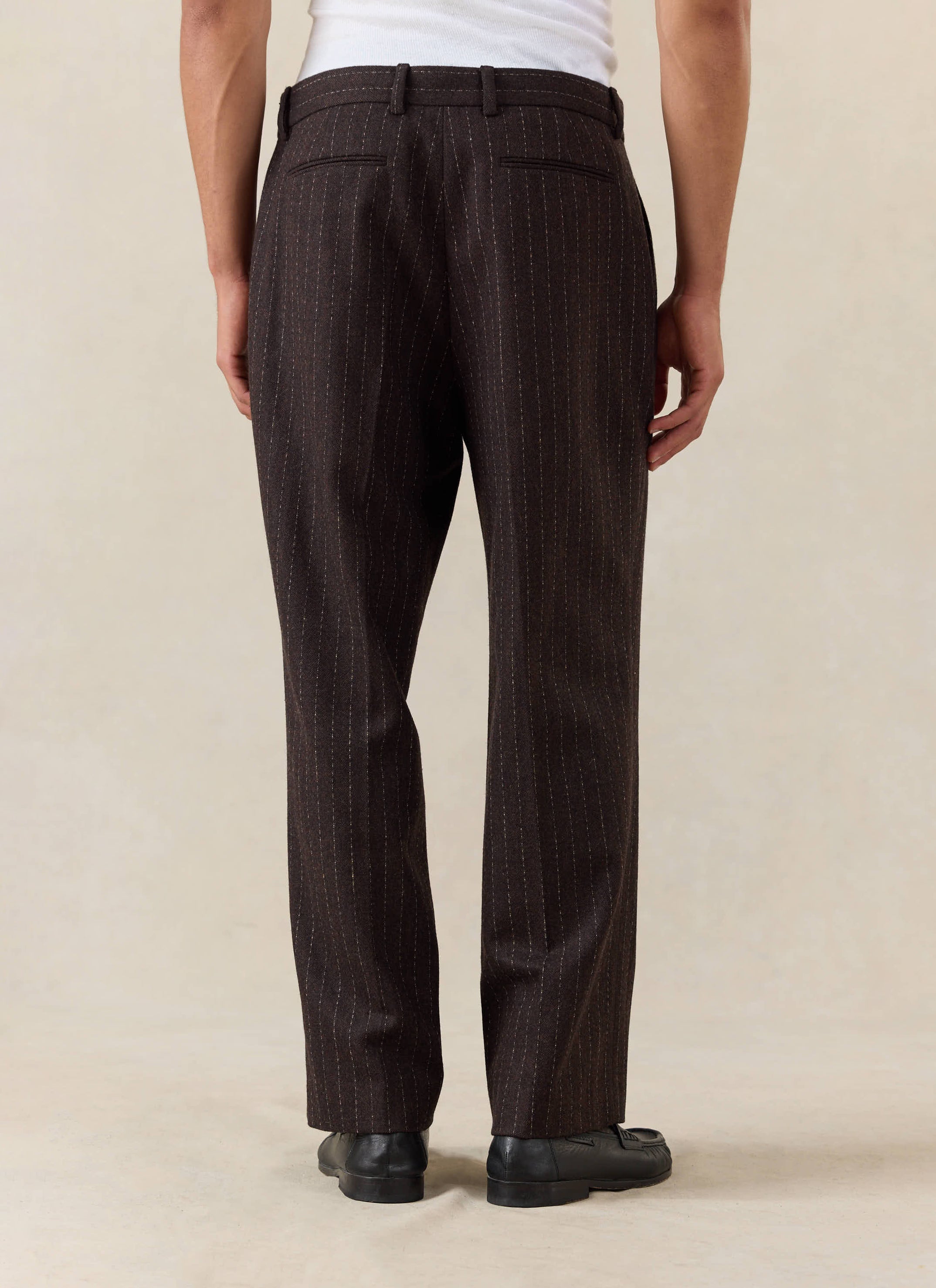 Percival Clifton Pinstripe Pleated Tailored Trousers in espresso wool, seen from the back and styled with black loafers.
