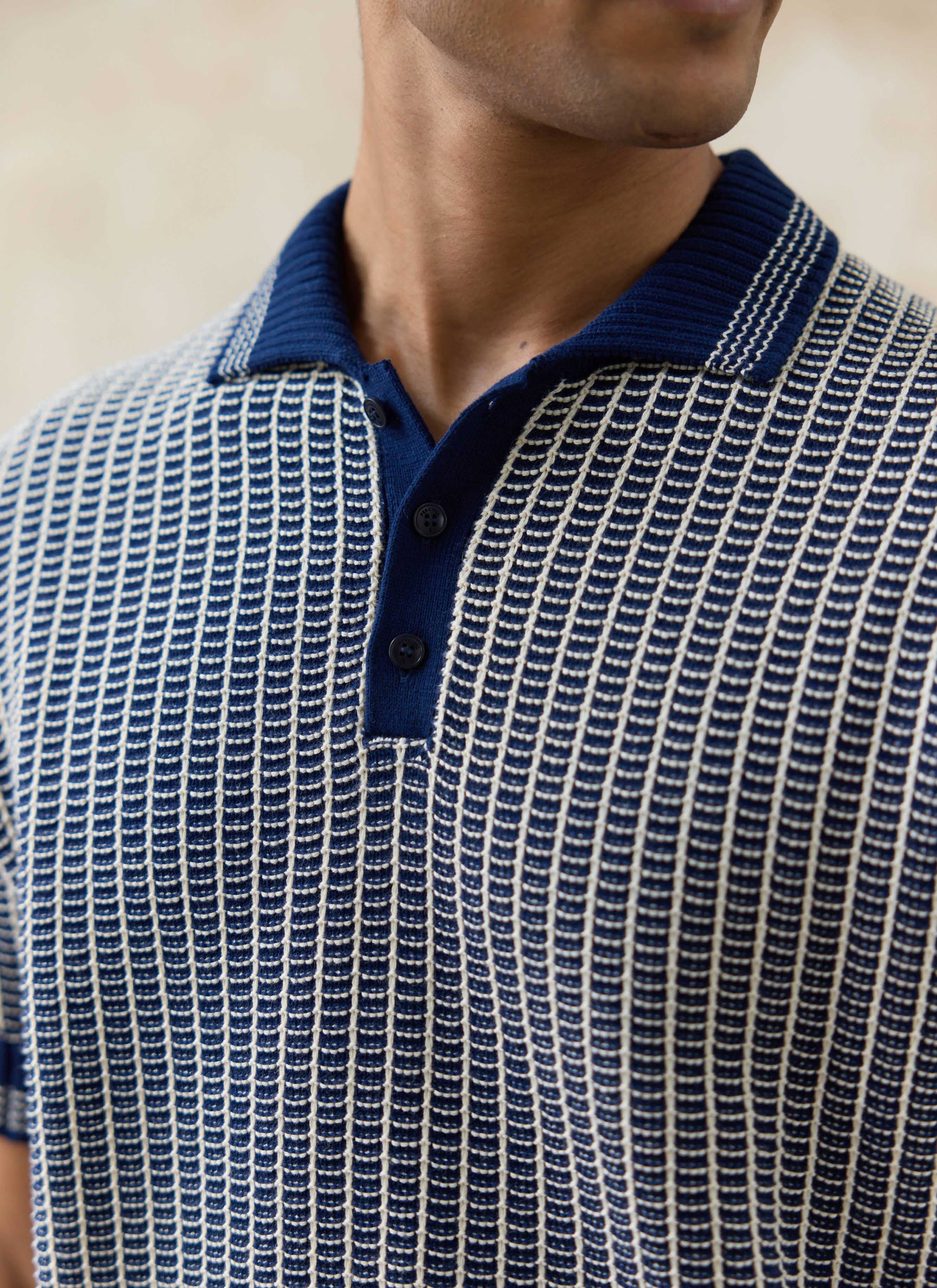 Close-up of the navy Claude Knitted Polo by Percival, featuring a two-tone textured cotton knit and ribbed collar.