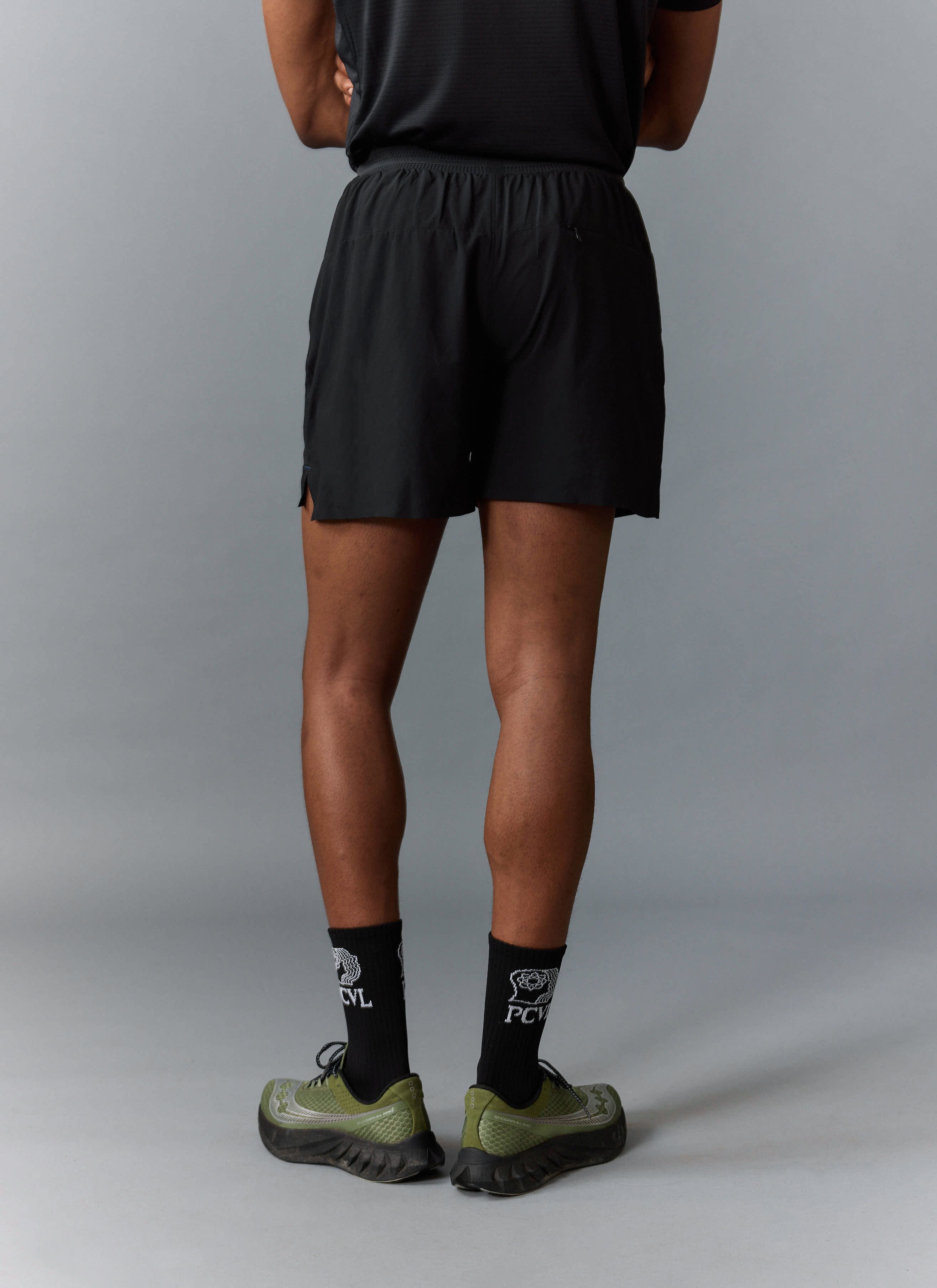 A model from behind wearing the black PCVL Performance Shorts and matching PCVL branded socks from Percival.