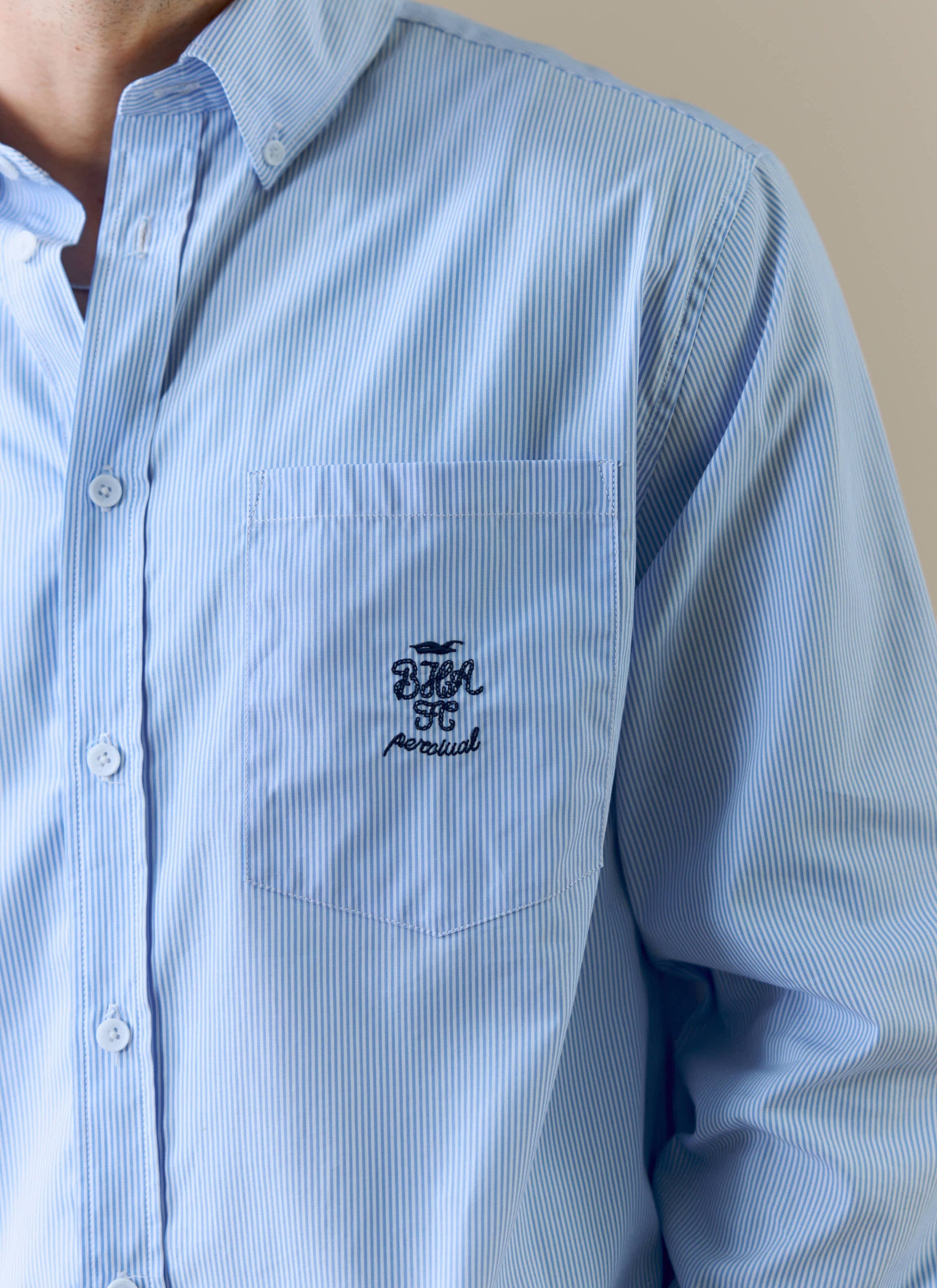 A close-up of the embroidered Brighton & Hove Albion F.C. logo on the pocket of the striped Pearce shirt by Percival.