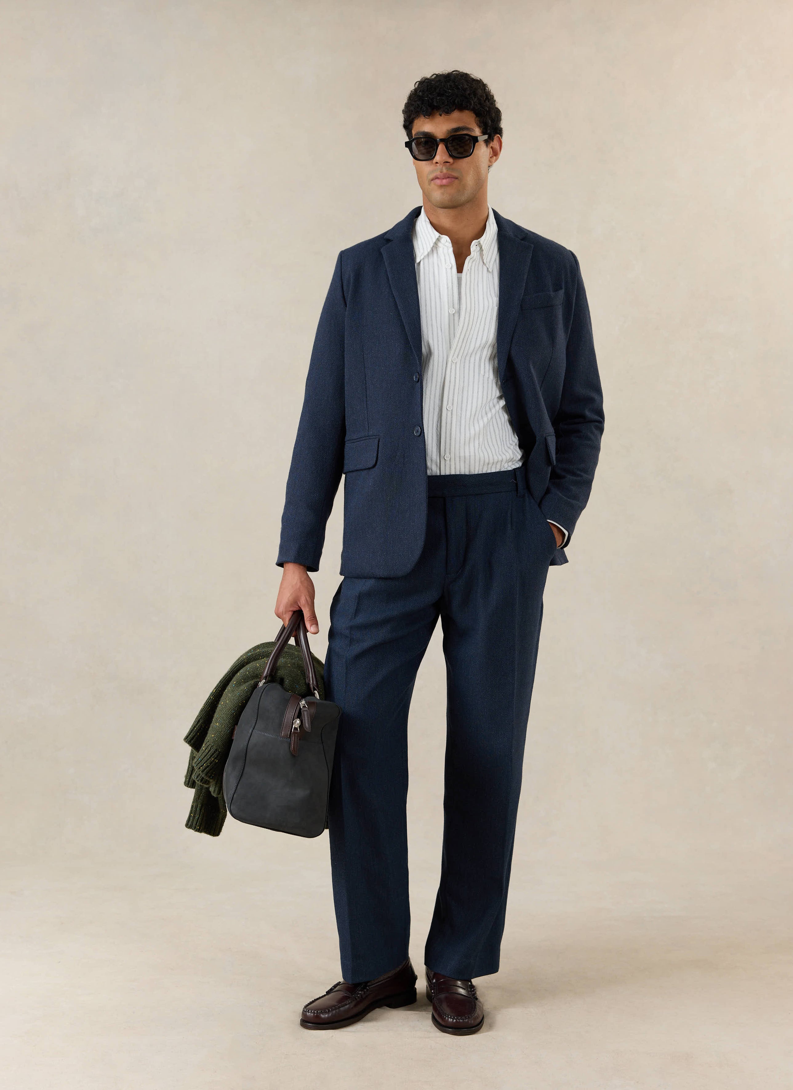A model wears the Percival Stanley Tailored Blazer and Percival Stanley Pleated Tailored Trousers in navy herringbone.