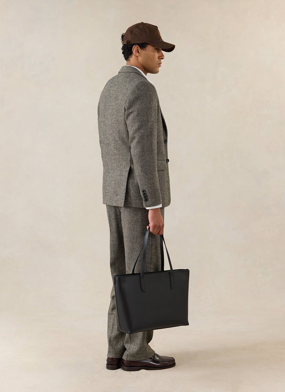 A model wears the Percival Wilde Tailored Blazer in Birdseye Wool Grey, styled with matching trousers and a black tote.