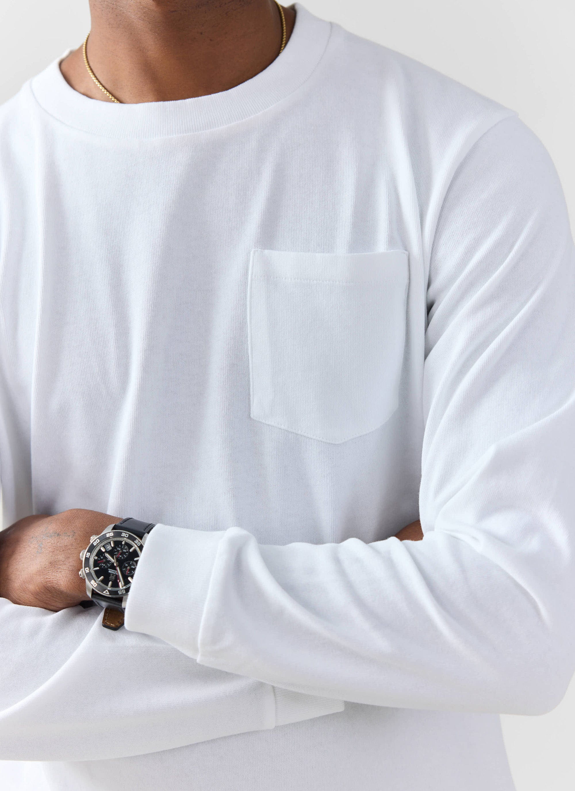 Close up of a model wearing the white Long Sleeve Pocket T Shirt from Percival, showing the chest pocket detail.