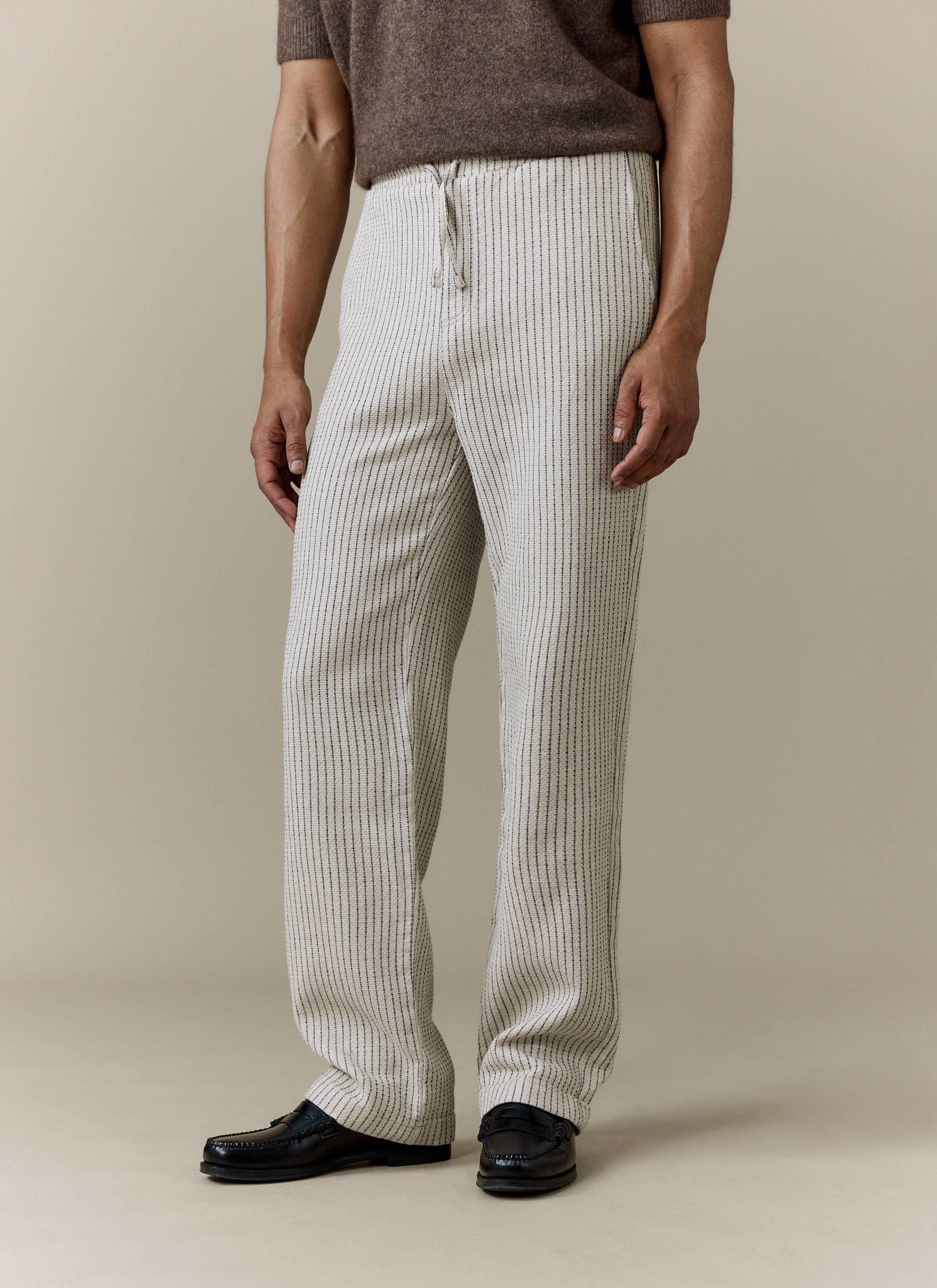 A model wears the Percival Sorrento Wide Leg Trousers in ecru, styled with a brown knitted top and black loafers.