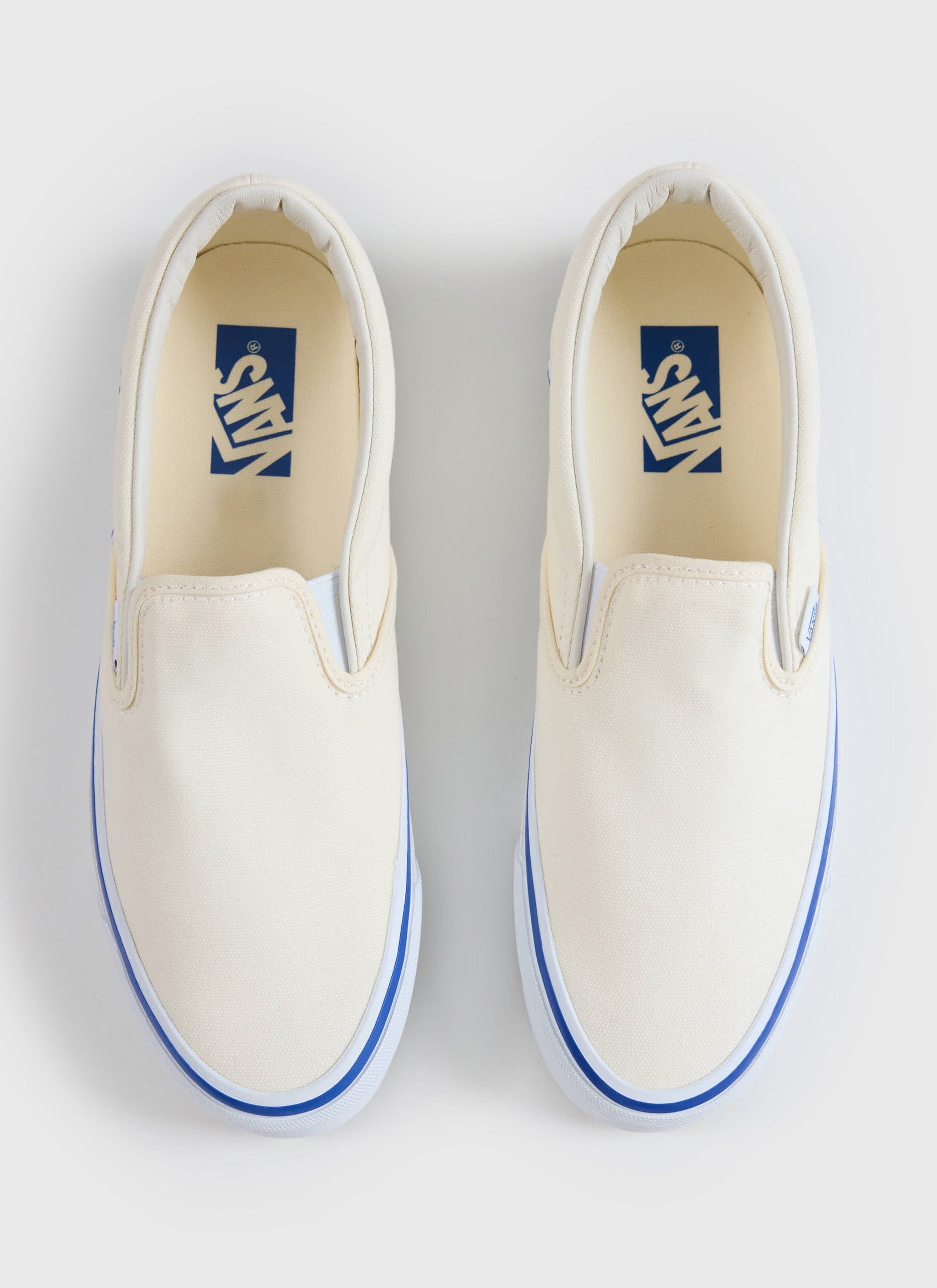 A top-down shot of the Vans Slip-On Reissue 98 shoes in off white canvas with blue foxing, from Percival.