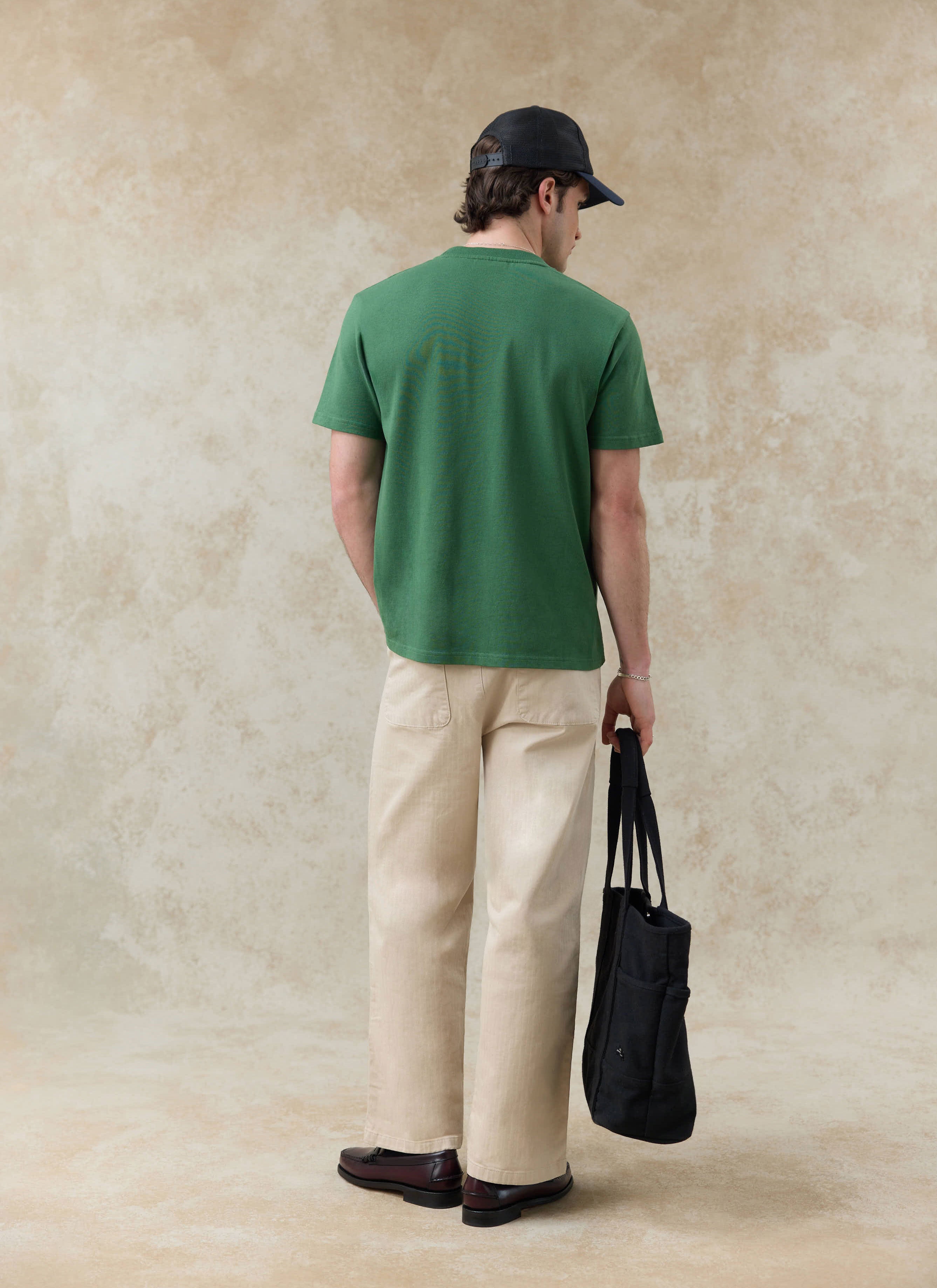 Percival Davies forest green organic cotton t-shirt, styled with beige trousers and seen from the back.