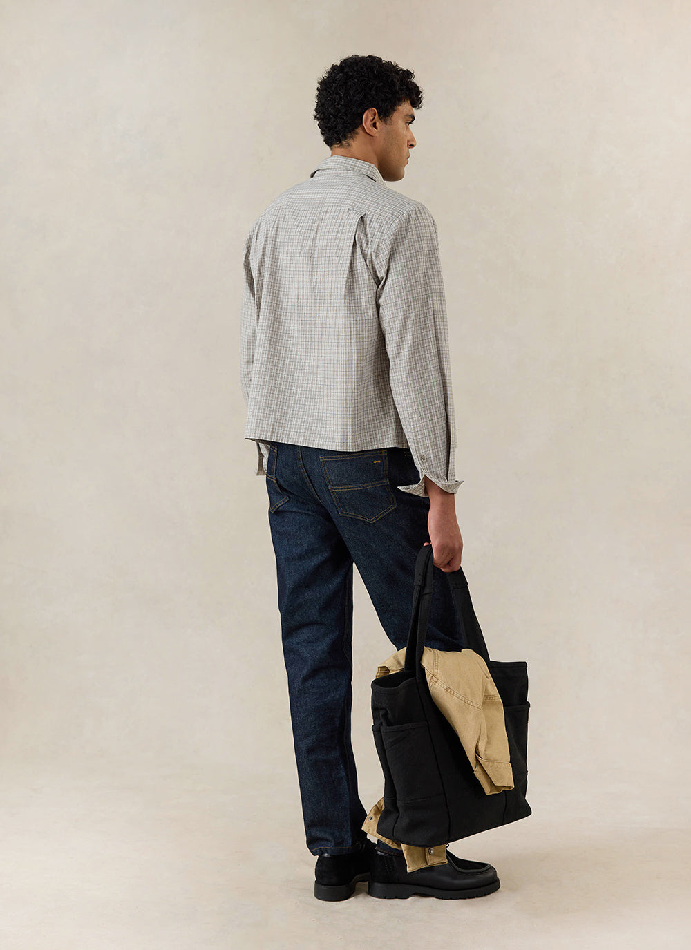 Rear view of the Percival Hinsley Boxy Long Sleeve Shirt in cream check cotton, styled with dark jeans and a black tote bag.