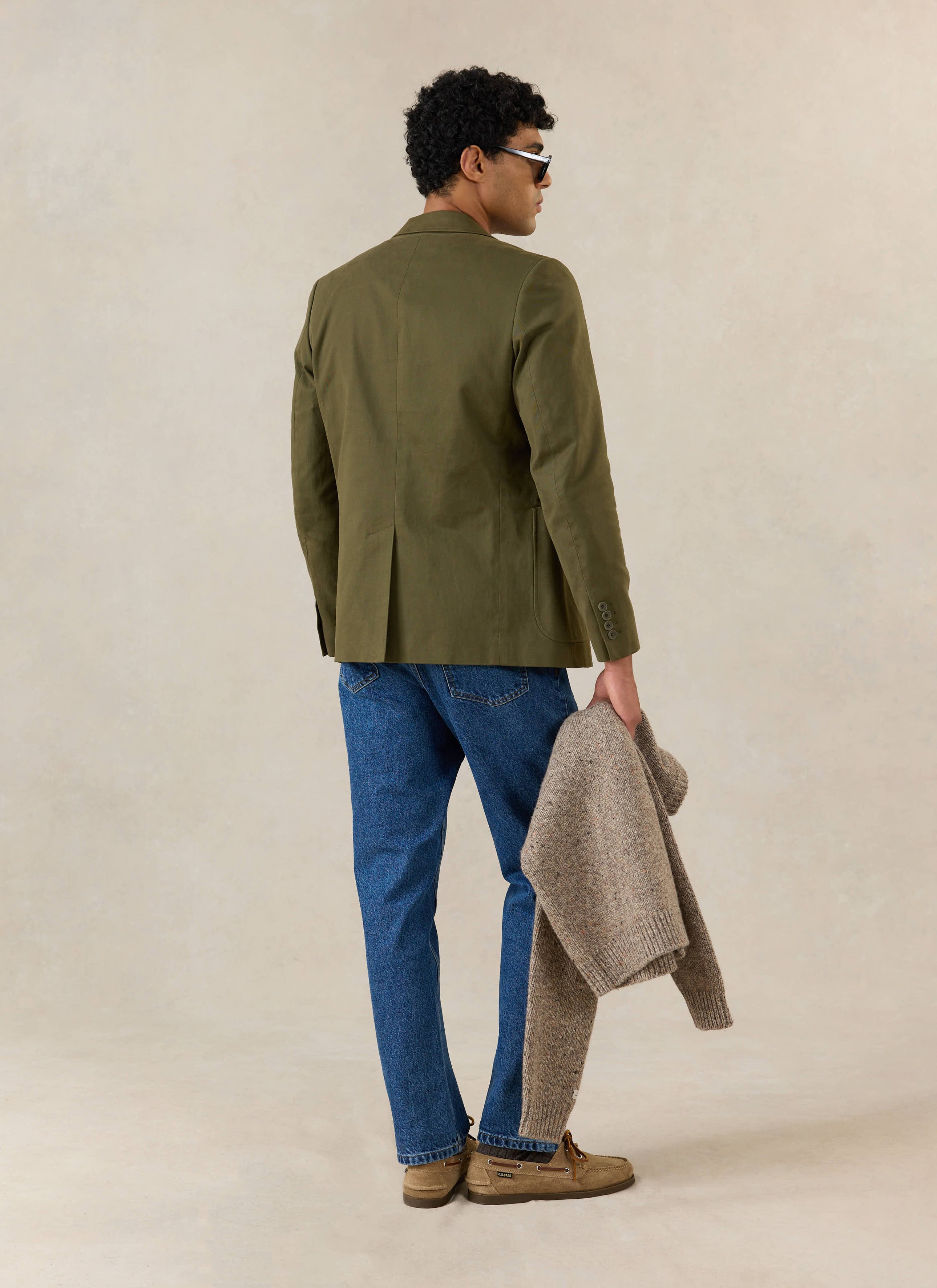 A model wears the Percival Tailored Blazer in Forest Green Brushed Moleskin from behind, with blue jeans and boat shoes.