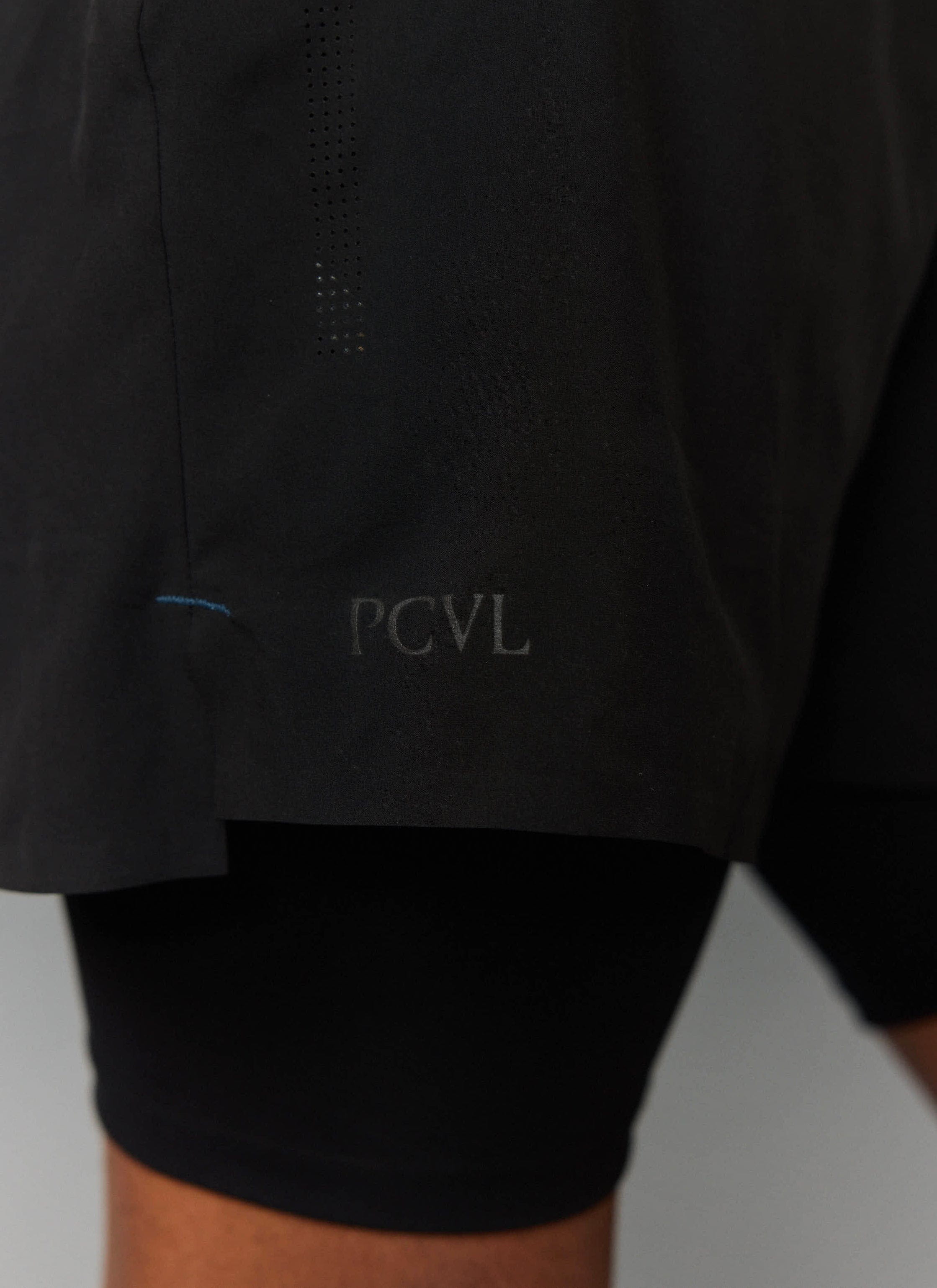 Close-up detail of the black PCVL 2 in 1 Shorts from Percival, showing the tonal logo and breathable perforations.